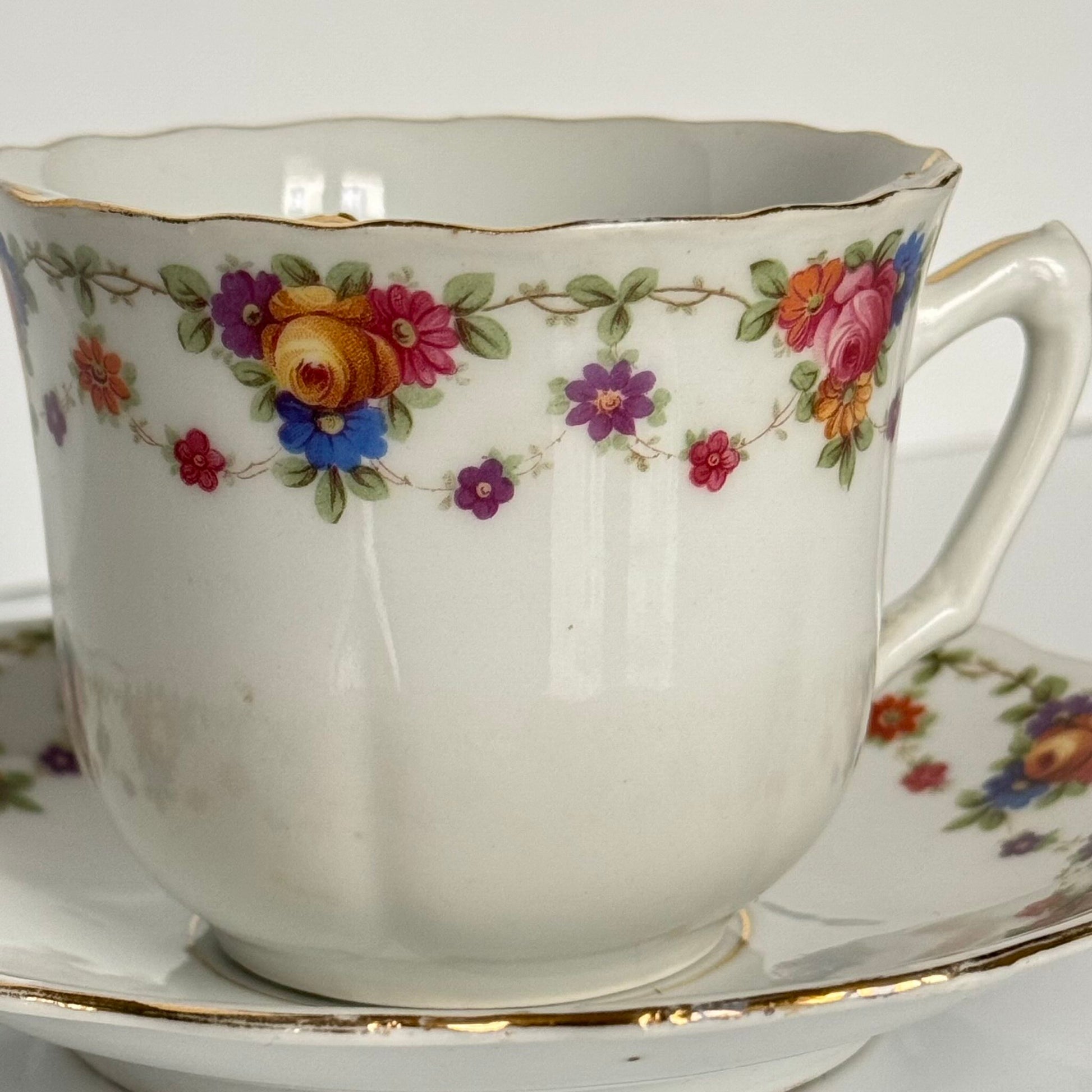 English: K. Steinmann Silesia porcelain moustache cup and saucer, floral design, made c.1910–1930, marked K.St. T. SILESIA; 日本語: K.シュタインマン製シレジア磁器のマスタッシュカップ＆ソーサー、フラワーガーランド、1910〜1930年頃製造、K.St. T. SILESIAのサインあり; Français: Tasse à moustache et soucoupe en porcelaine de Silesia par K. Steinmann, décor floral, fabriquée vers 1910–1930, signée K.St. T. SILESIA.