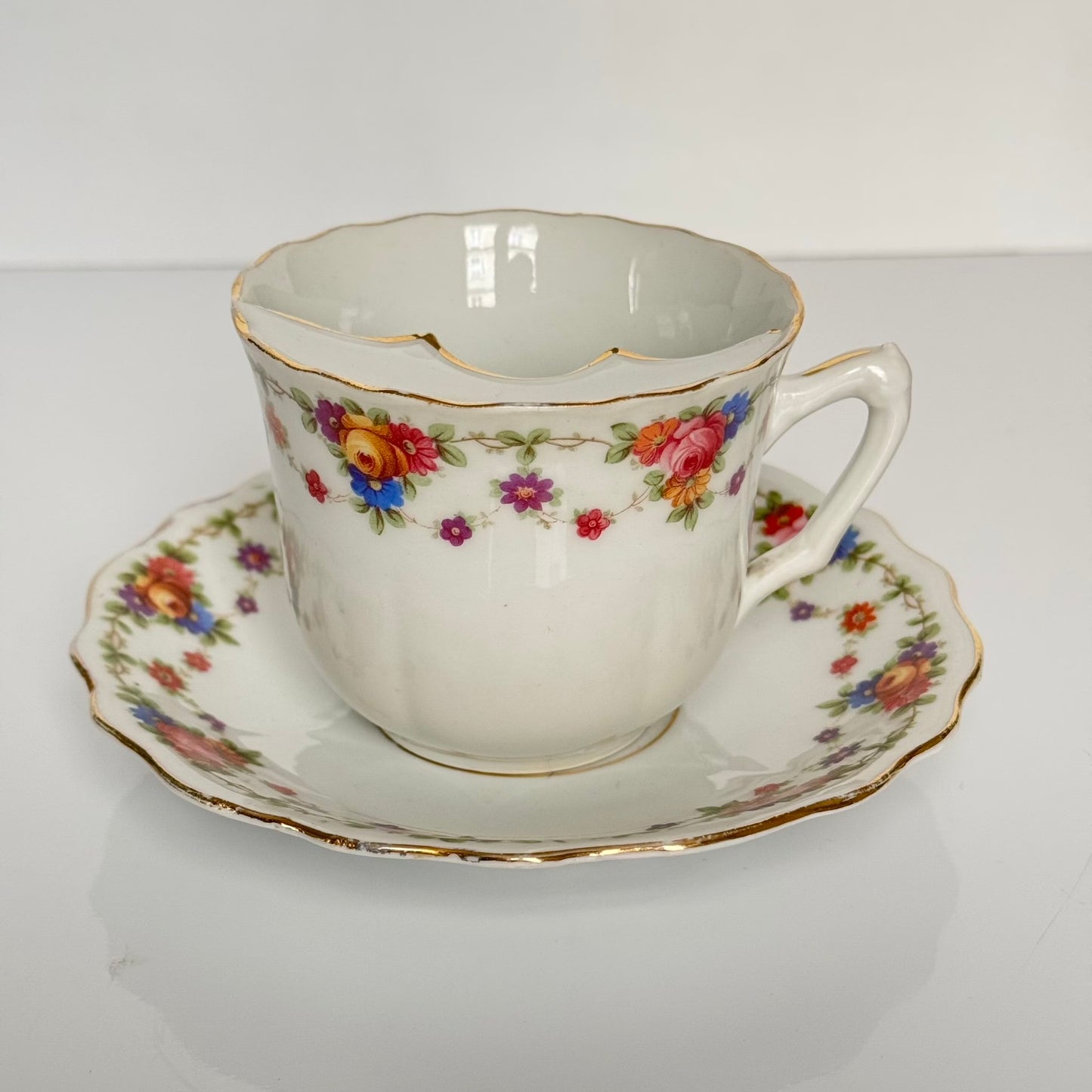 English: K. Steinmann Silesia porcelain moustache cup and saucer, floral design, made c.1910–1930, marked K.St. T. SILESIA; 日本語: K.シュタインマン製シレジア磁器のマスタッシュカップ＆ソーサー、フラワーガーランド、1910〜1930年頃製造、K.St. T. SILESIAのサインあり; Français: Tasse à moustache et soucoupe en porcelaine de Silesia par K. Steinmann, décor floral, fabriquée vers 1910–1930, signée K.St. T. SILESIA.