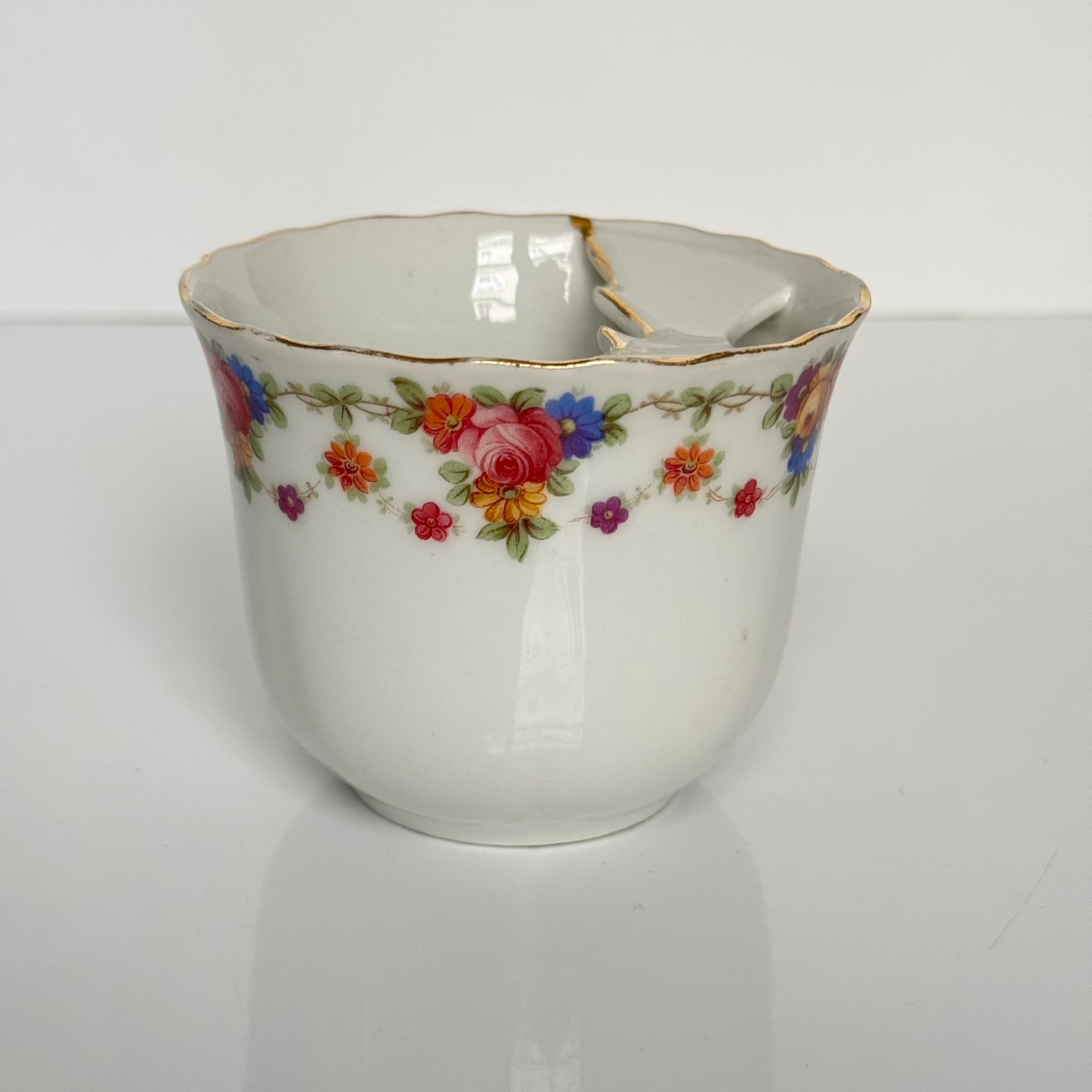 English: K. Steinmann Silesia porcelain moustache cup and saucer, floral design, made c.1910–1930, marked K.St. T. SILESIA; 日本語: K.シュタインマン製シレジア磁器のマスタッシュカップ＆ソーサー、フラワーガーランド、1910〜1930年頃製造、K.St. T. SILESIAのサインあり; Français: Tasse à moustache et soucoupe en porcelaine de Silesia par K. Steinmann, décor floral, fabriquée vers 1910–1930, signée K.St. T. SILESIA.