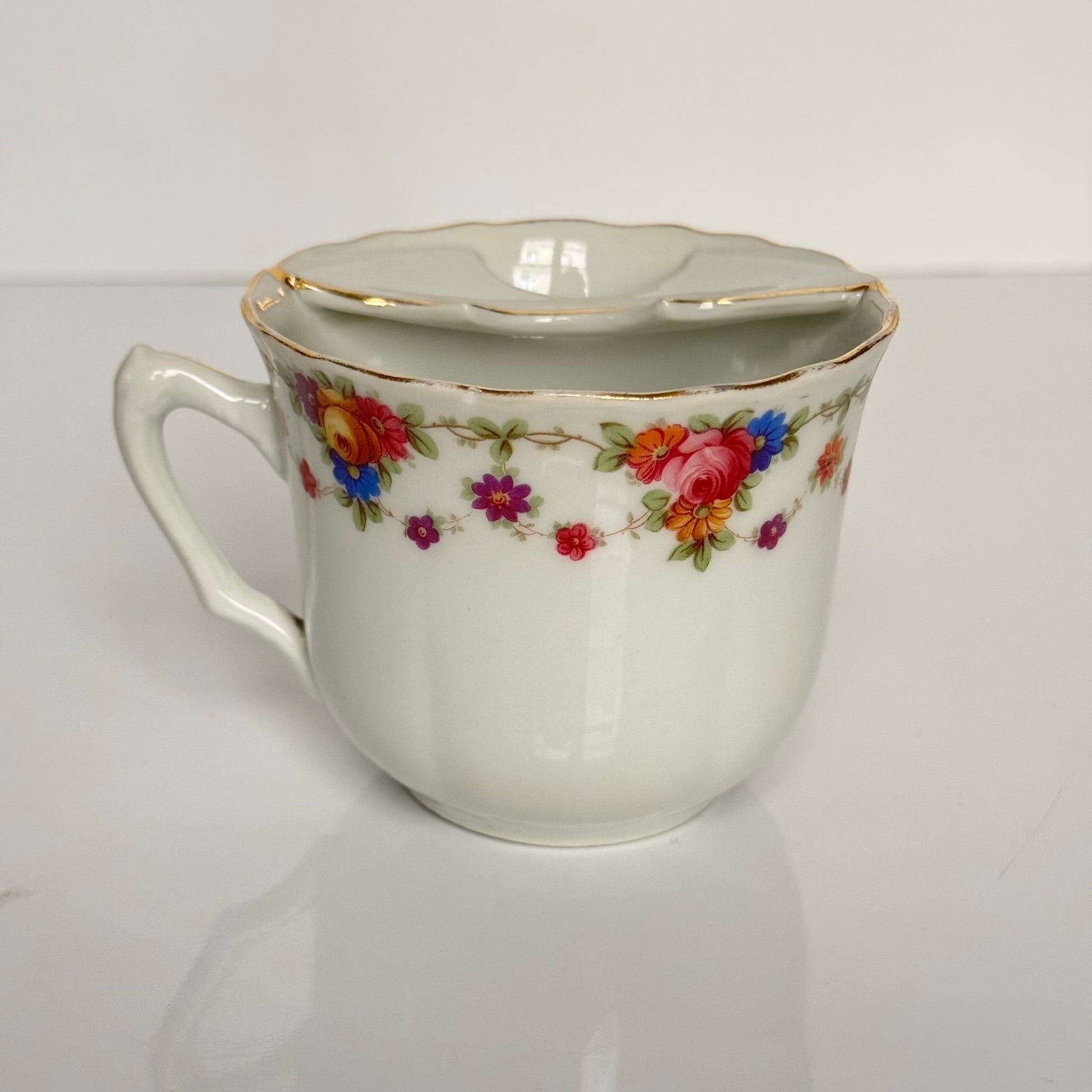 English: K. Steinmann Silesia porcelain moustache cup and saucer, floral design, made c.1910–1930, marked K.St. T. SILESIA; 日本語: K.シュタインマン製シレジア磁器のマスタッシュカップ＆ソーサー、フラワーガーランド、1910〜1930年頃製造、K.St. T. SILESIAのサインあり; Français: Tasse à moustache et soucoupe en porcelaine de Silesia par K. Steinmann, décor floral, fabriquée vers 1910–1930, signée K.St. T. SILESIA.