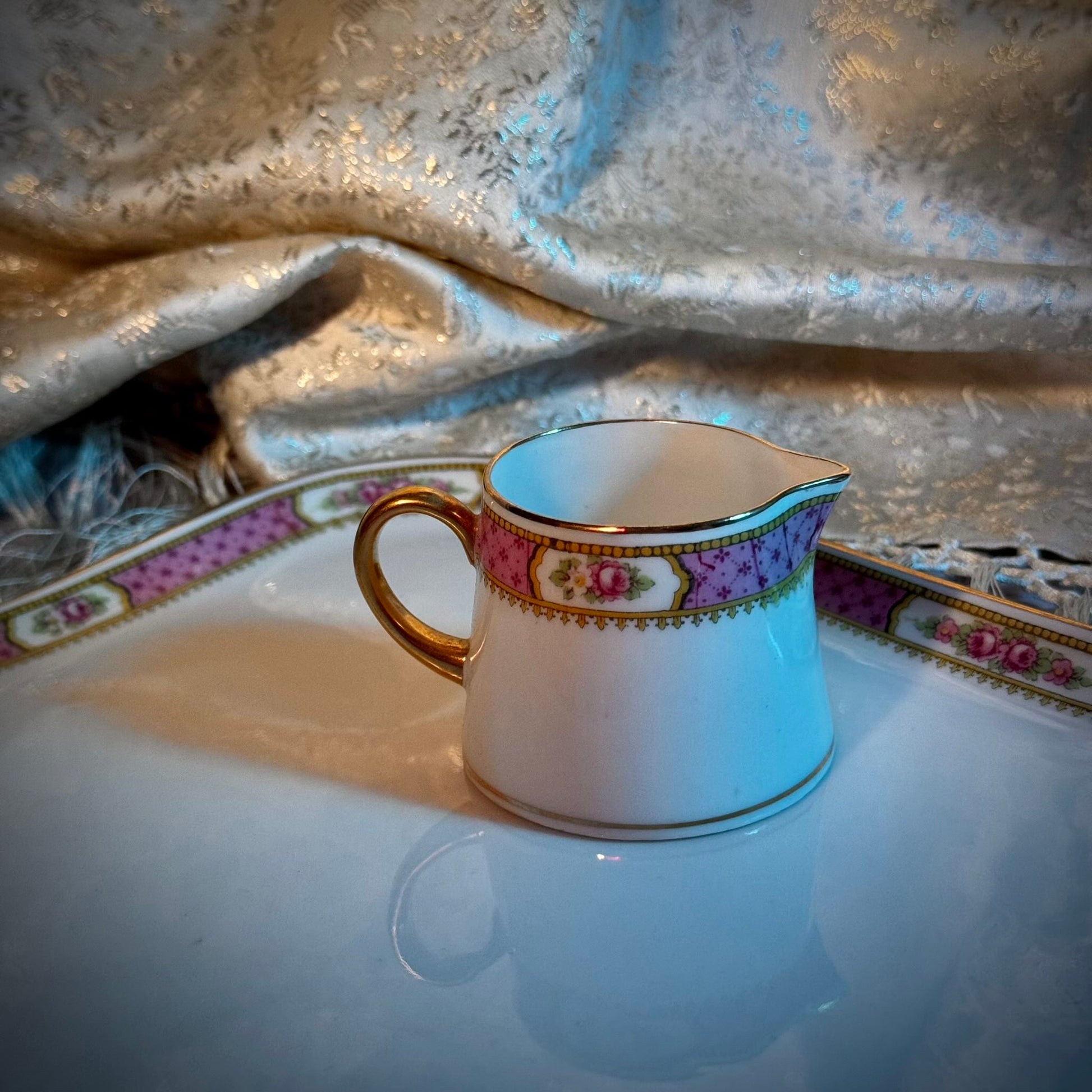 This is a Limoges porcelain milk jug with a delicate floral rose design, made by F. Paulhat. It showcases fine craftsmanship typical of Limoges porcelain.