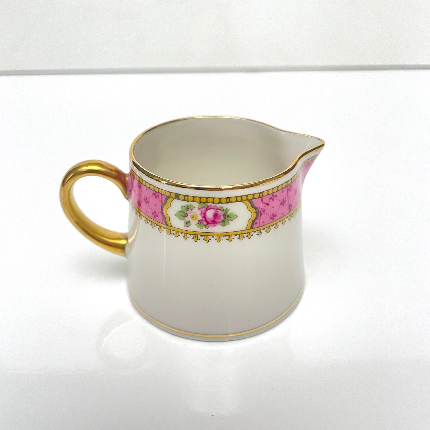 This is a Limoges porcelain milk jug with a delicate floral rose design, made by F. Paulhat. It showcases fine craftsmanship typical of Limoges porcelain.