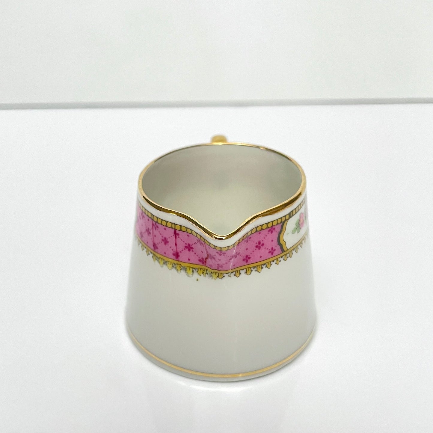 This is a Limoges porcelain milk jug with a delicate floral rose design, made by F. Paulhat. It showcases fine craftsmanship typical of Limoges porcelain.