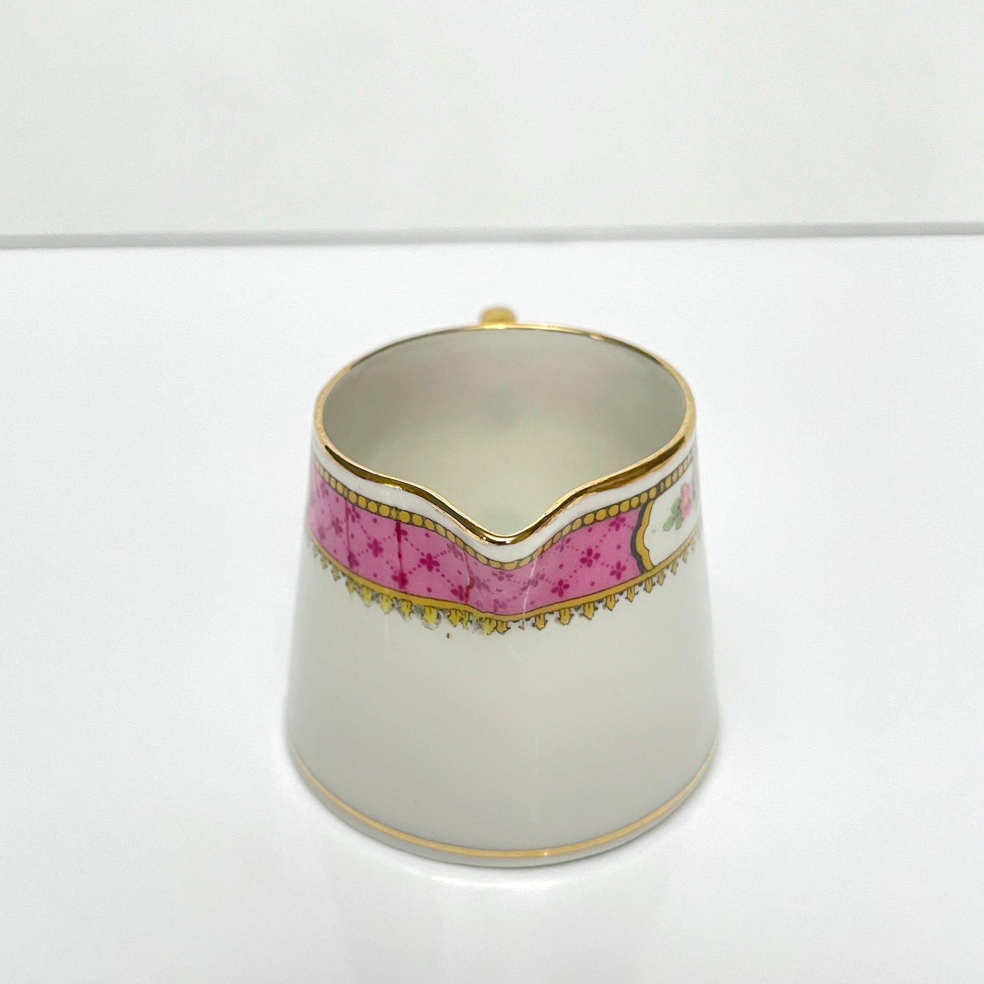 This is a Limoges porcelain milk jug with a delicate floral rose design, made by F. Paulhat. It showcases fine craftsmanship typical of Limoges porcelain.