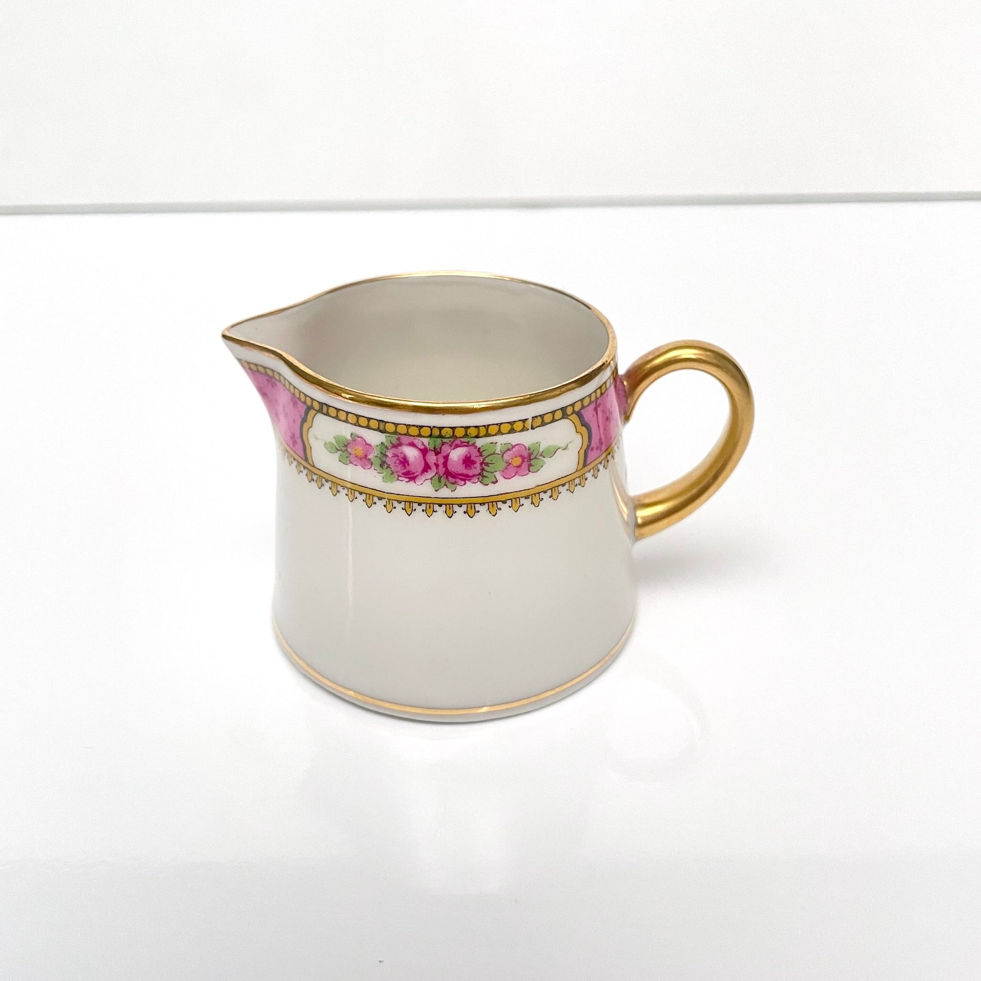 This is a Limoges porcelain milk jug with a delicate floral rose design, made by F. Paulhat. It showcases fine craftsmanship typical of Limoges porcelain.