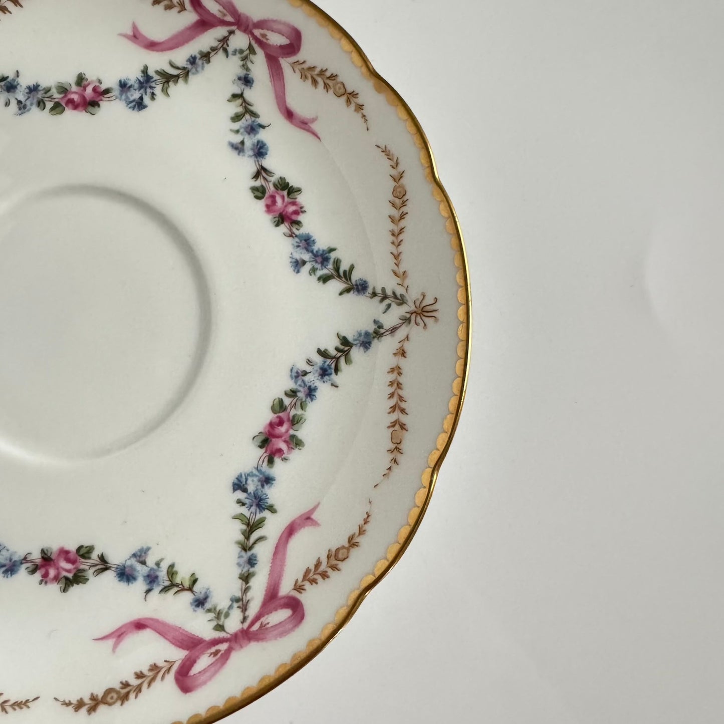 Limoges porcelain plate, Comte d’Artois model, with a Sèvres-inspired ribbon and floral design. Ideal for serving macarons or small desserts. Vintage from the 20th century onwards.
