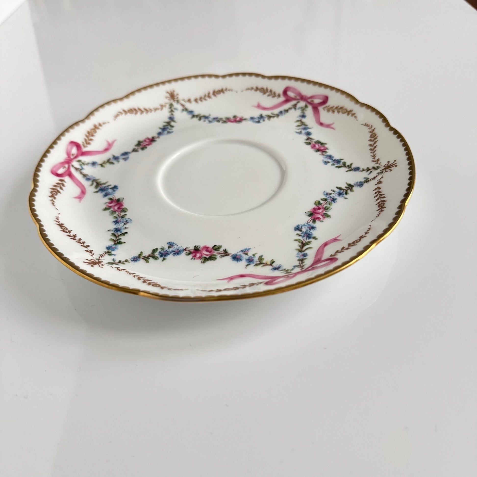 Limoges porcelain plate, Comte d’Artois model, with a Sèvres-inspired ribbon and floral design. Ideal for serving macarons or small desserts. Vintage from the 20th century onwards.