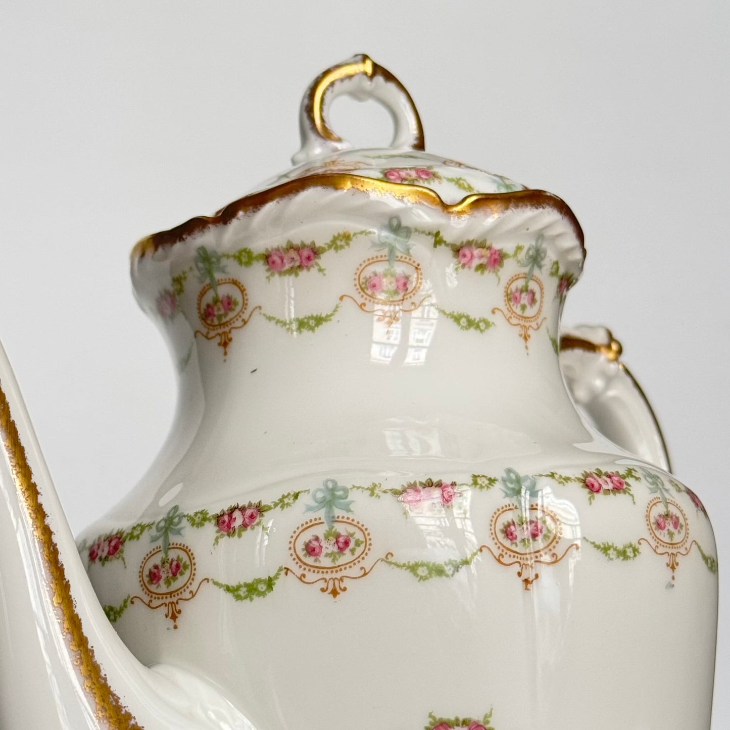 Limoges porcelain tea/coffee pot and sugar pot set with a floral and ribbon design, exuding elegance.