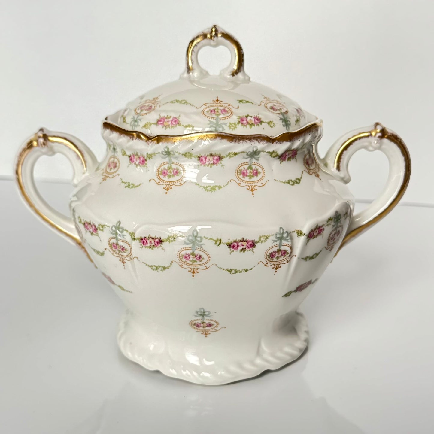 Limoges porcelain tea/coffee pot and sugar pot set with a floral and ribbon design, exuding elegance.