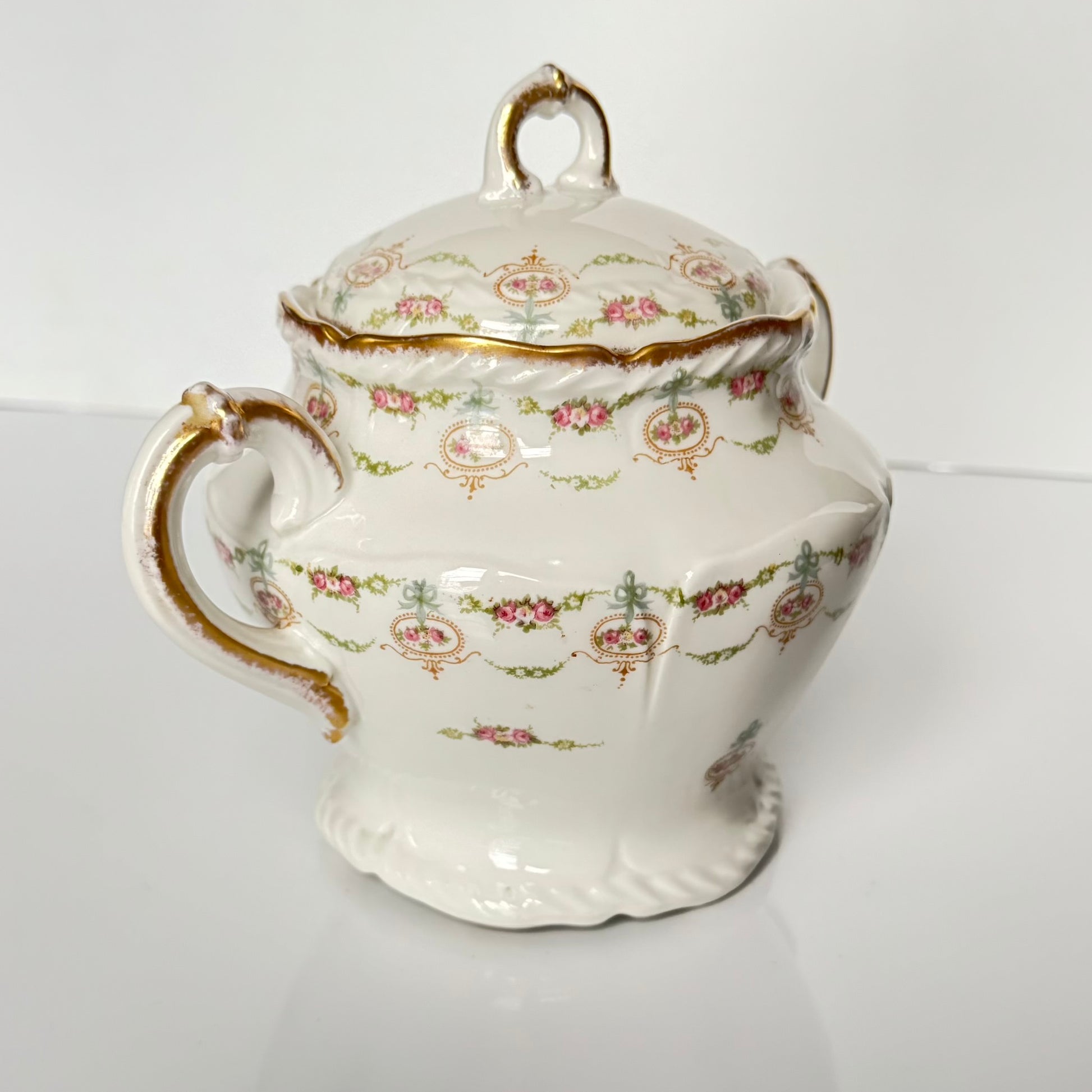 Limoges porcelain tea/coffee pot and sugar pot set with a floral and ribbon design, exuding elegance.