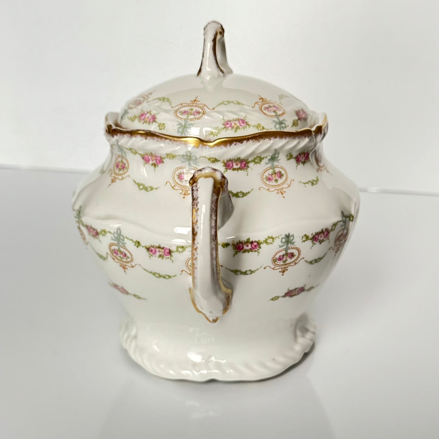 Limoges porcelain tea/coffee pot and sugar pot set with a floral and ribbon design, exuding elegance.
