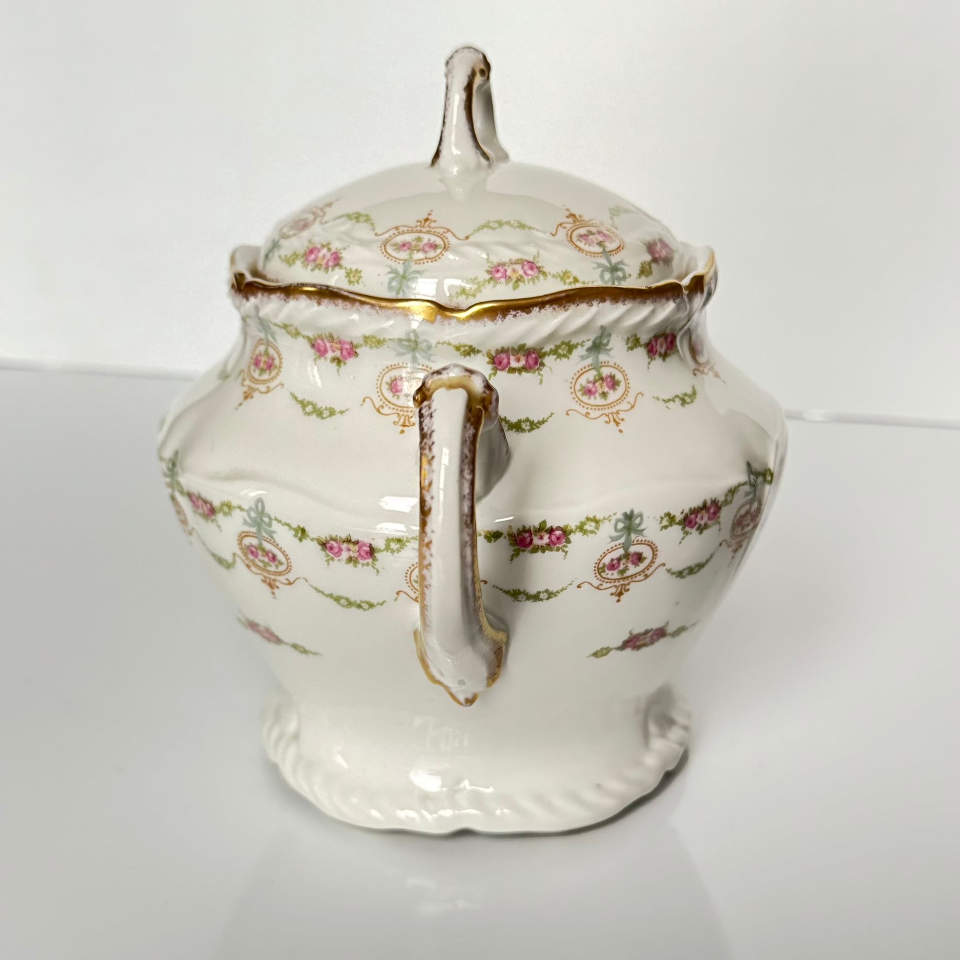 Limoges porcelain tea/coffee pot and sugar pot set with a floral and ribbon design, exuding elegance.