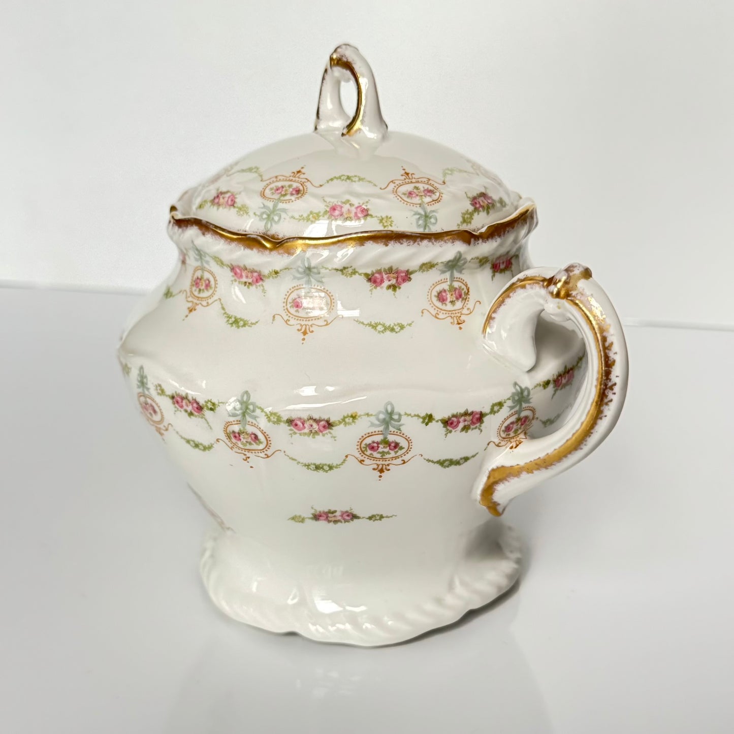 Limoges porcelain tea/coffee pot and sugar pot set with a floral and ribbon design, exuding elegance.