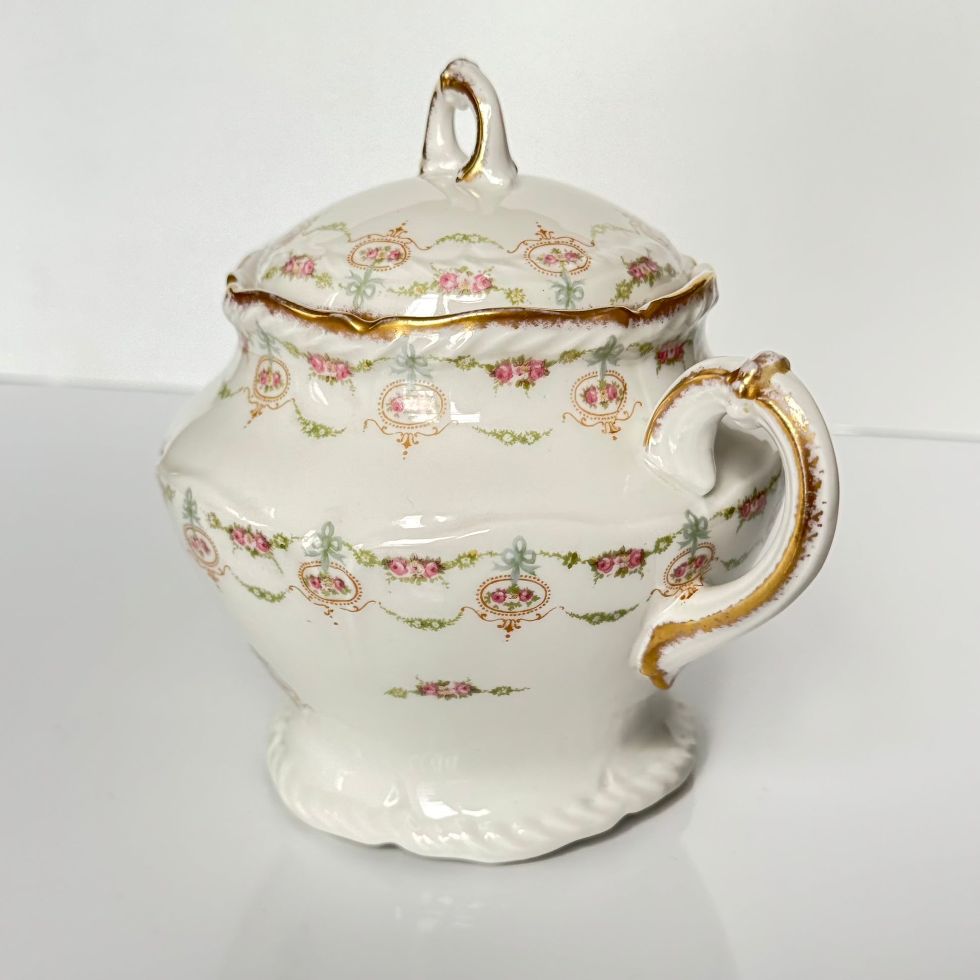 Limoges porcelain tea/coffee pot and sugar pot set with a floral and ribbon design, exuding elegance.