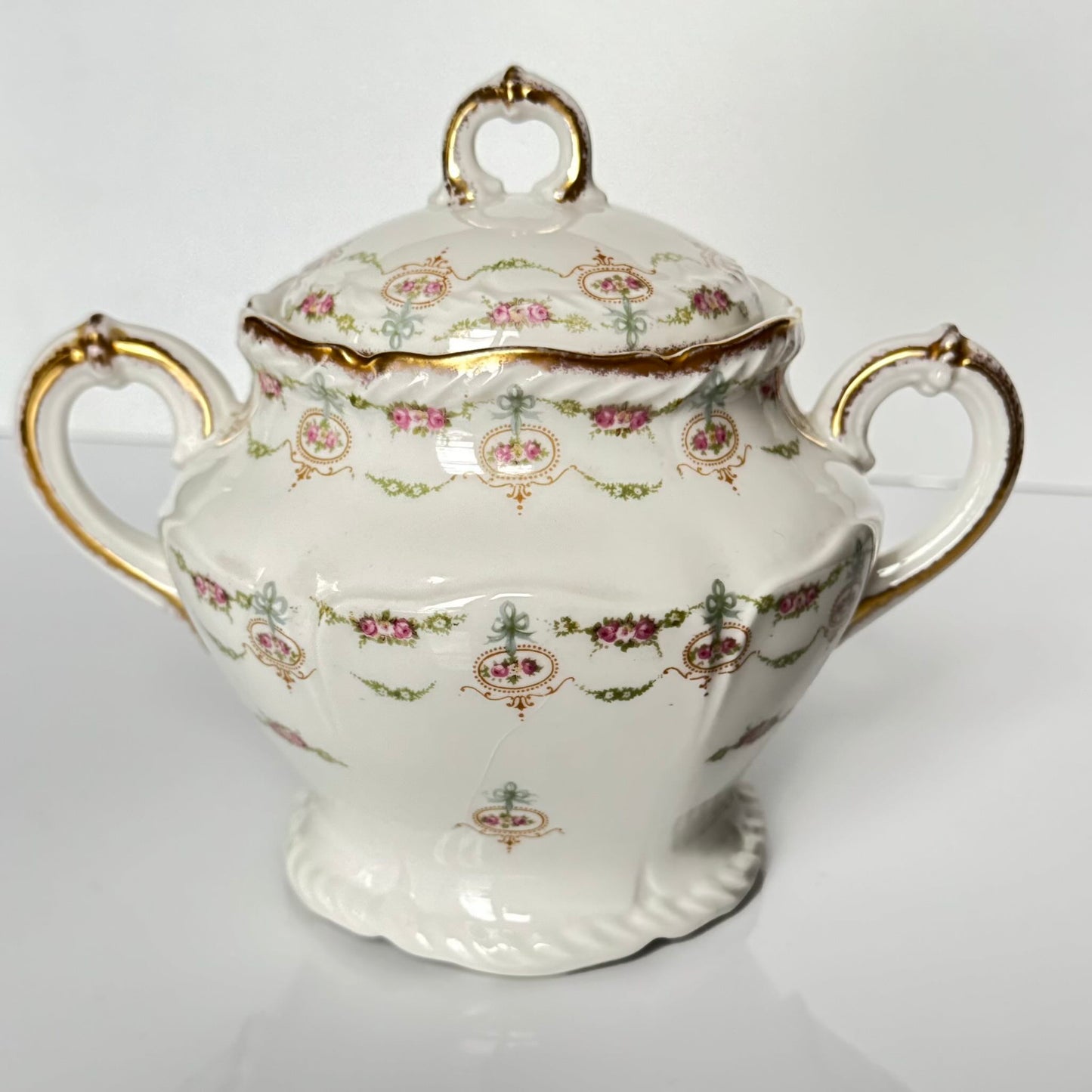 Limoges porcelain tea/coffee pot and sugar pot set with a floral and ribbon design, exuding elegance.