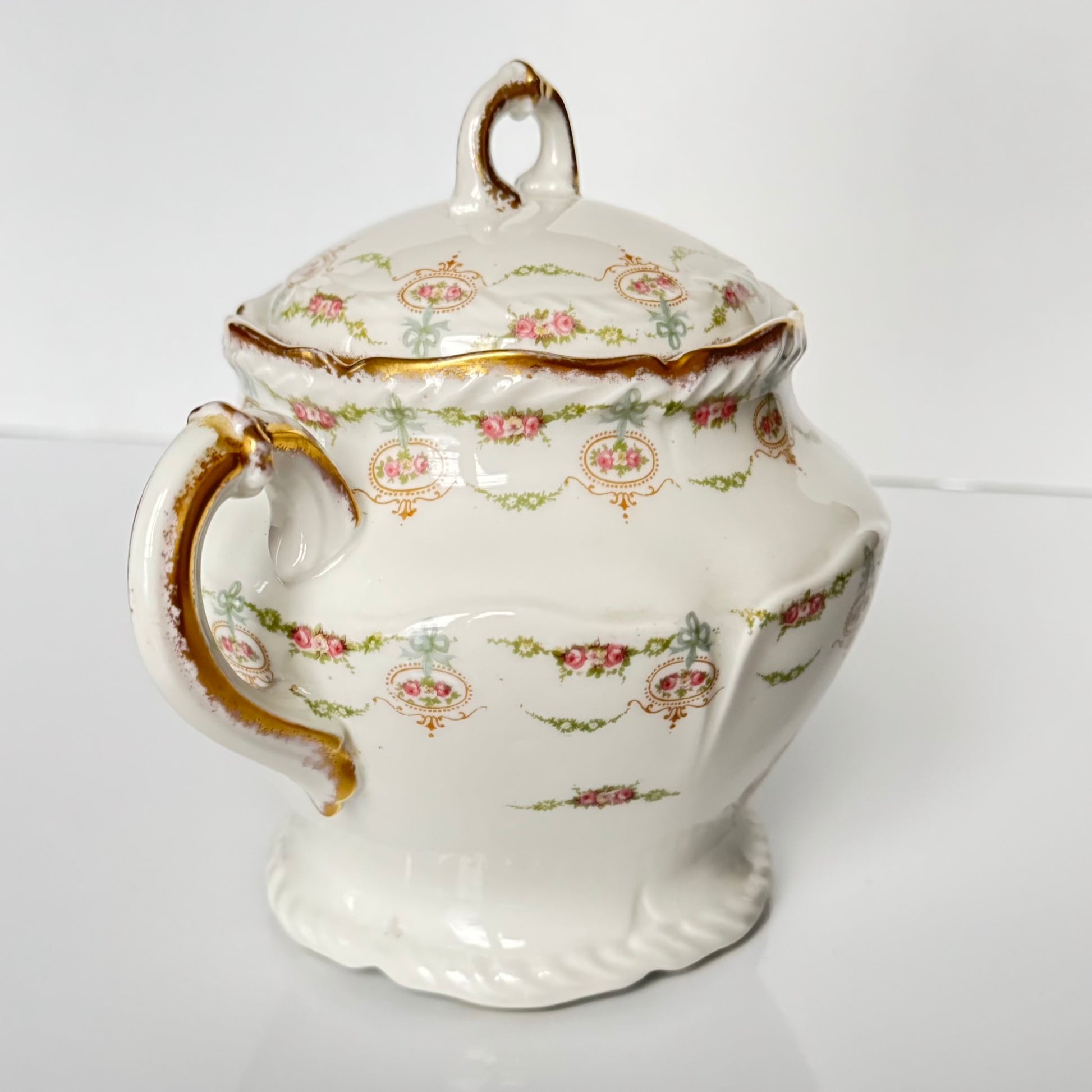 Limoges porcelain tea/coffee pot and sugar pot set with a floral and ribbon design, exuding elegance.