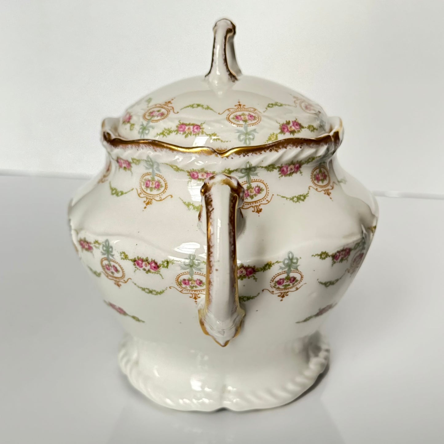 Limoges porcelain tea/coffee pot and sugar pot set with a floral and ribbon design, exuding elegance.