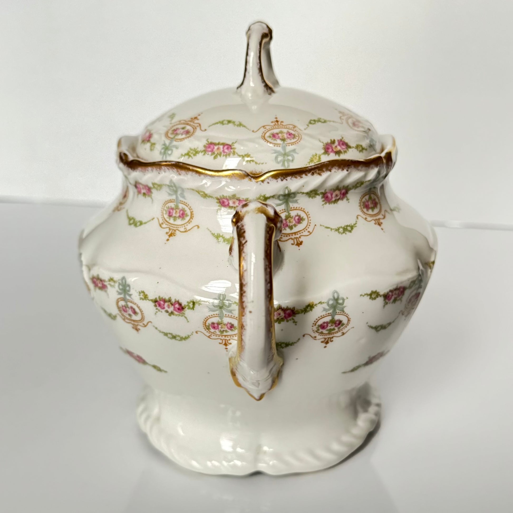 Limoges porcelain tea/coffee pot and sugar pot set with a floral and ribbon design, exuding elegance.