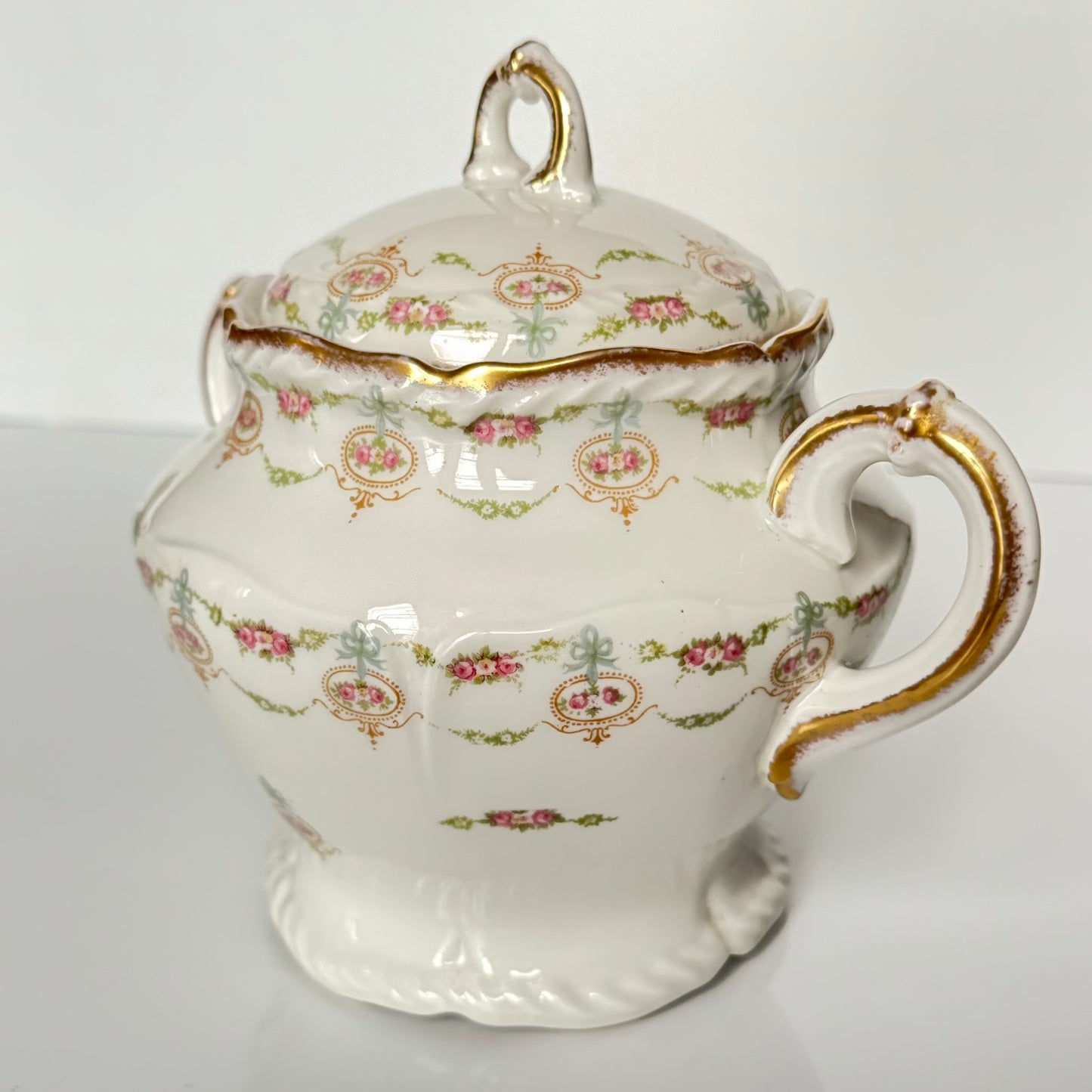 Limoges porcelain tea/coffee pot and sugar pot set with a floral and ribbon design, exuding elegance.