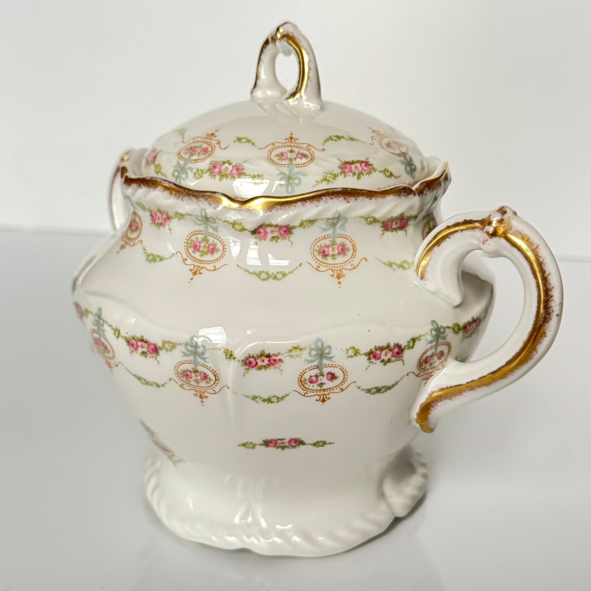Limoges porcelain tea/coffee pot and sugar pot set with a floral and ribbon design, exuding elegance.