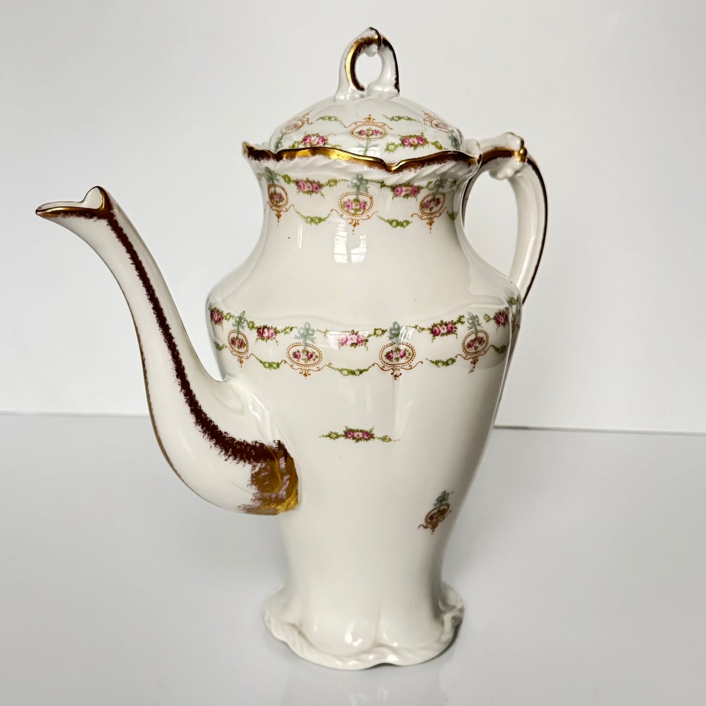 Limoges porcelain tea/coffee pot and sugar pot set with a floral and ribbon design, exuding elegance.