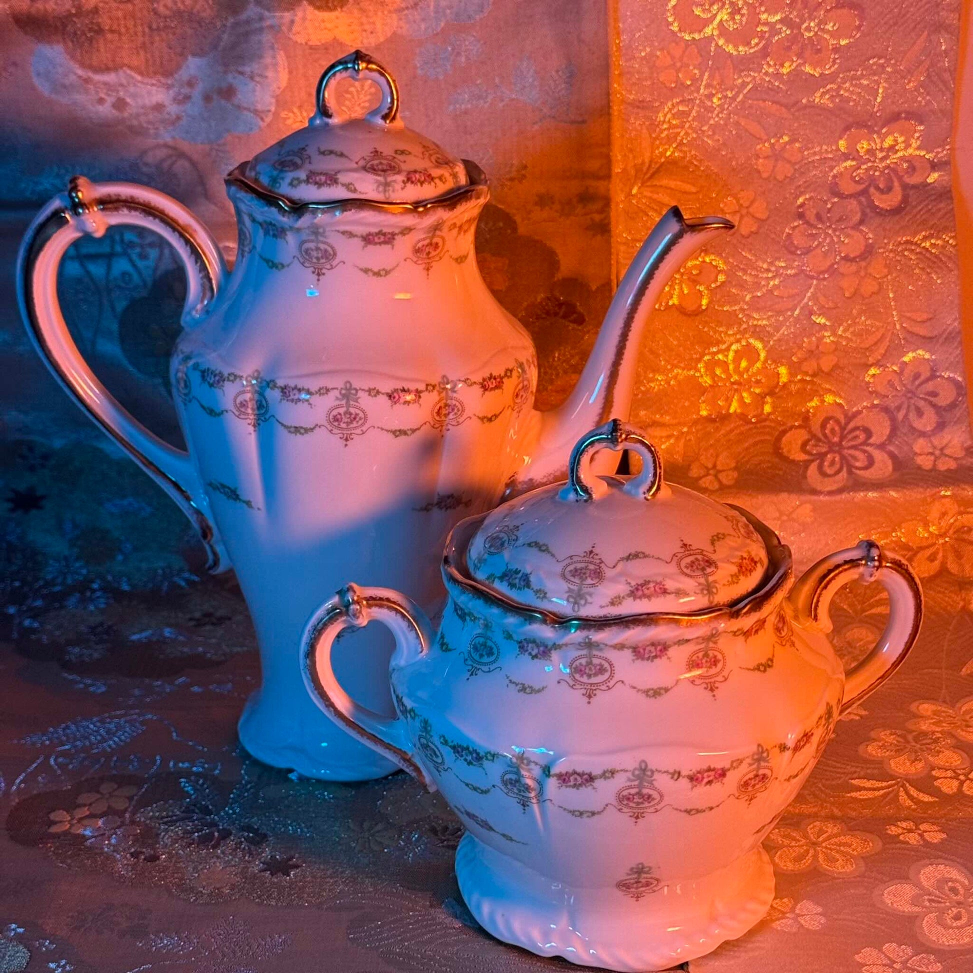 Limoges porcelain tea/coffee pot and sugar pot set with a floral and ribbon design, exuding elegance.