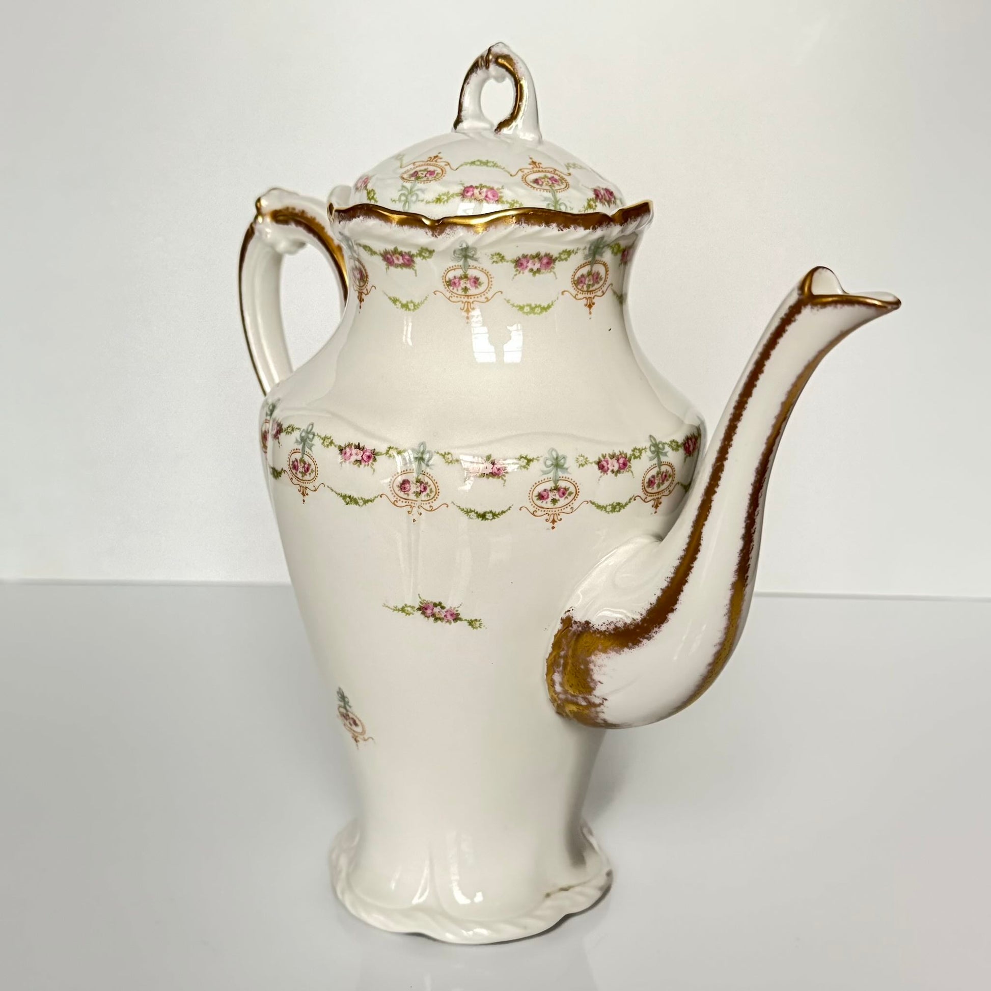 Limoges porcelain tea/coffee pot and sugar pot set with a floral and ribbon design, exuding elegance.