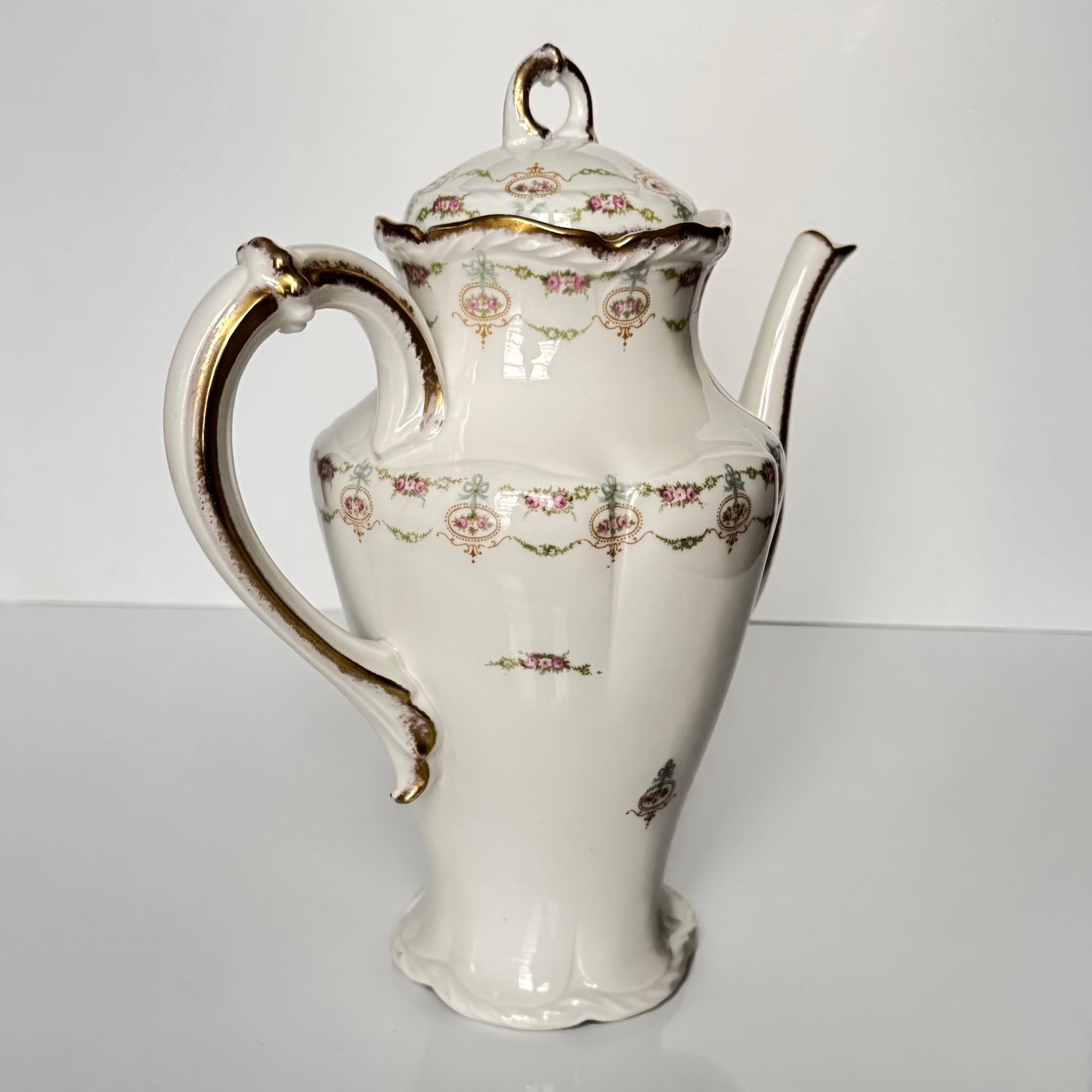 Limoges porcelain tea/coffee pot and sugar pot set with a floral and ribbon design, exuding elegance.
