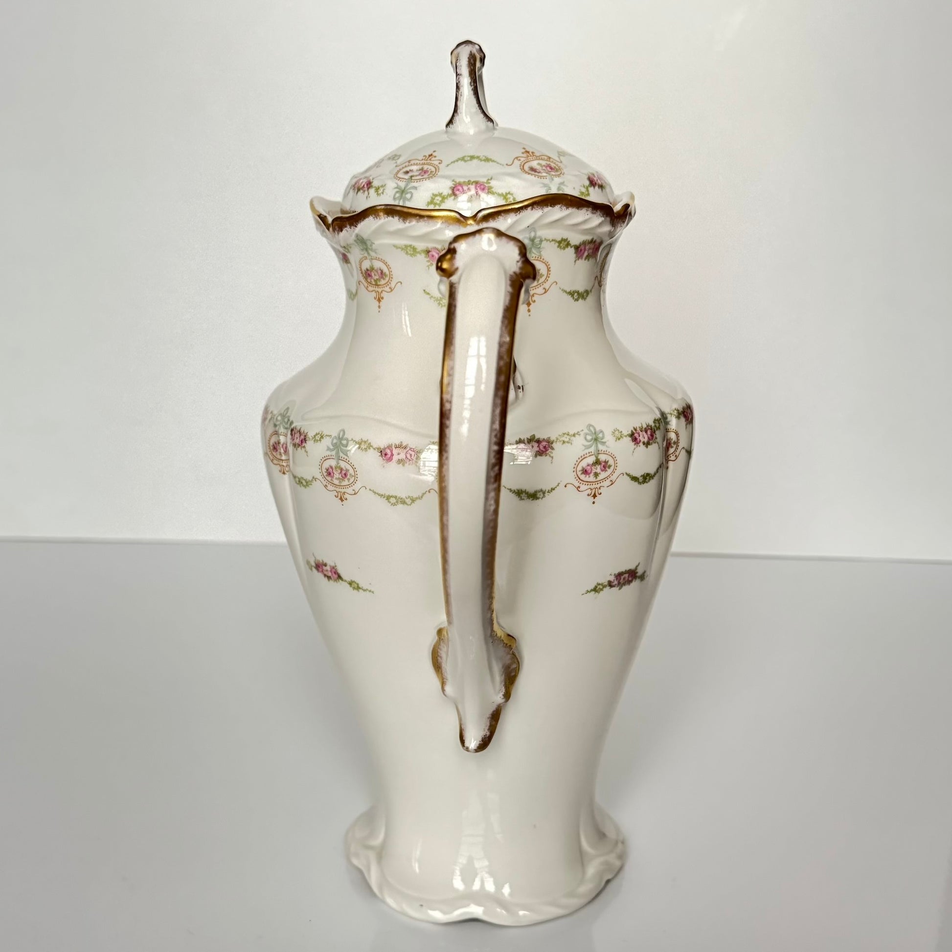Limoges porcelain tea/coffee pot and sugar pot set with a floral and ribbon design, exuding elegance.