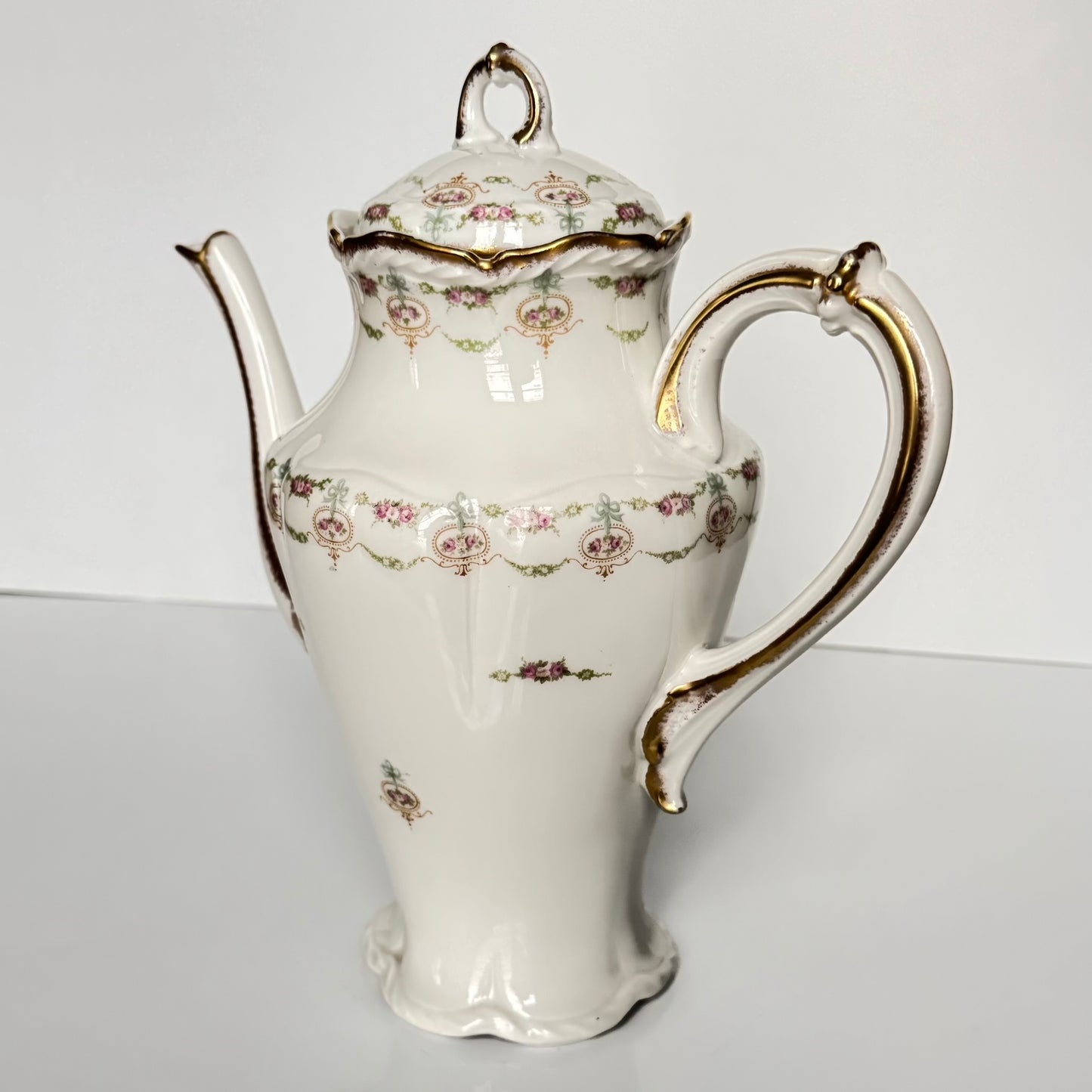 Limoges porcelain tea/coffee pot and sugar pot set with a floral and ribbon design, exuding elegance.