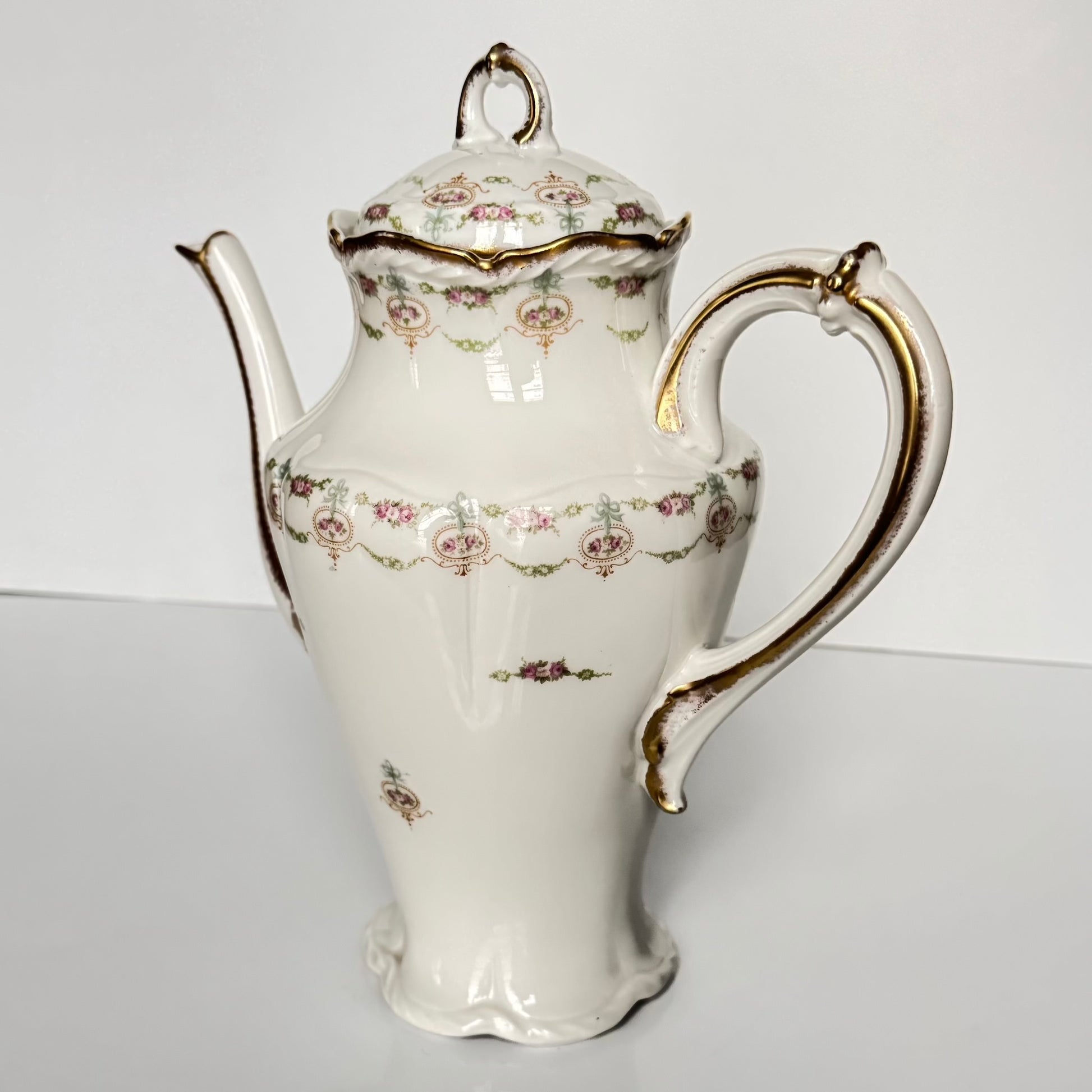 Limoges porcelain tea/coffee pot and sugar pot set with a floral and ribbon design, exuding elegance.