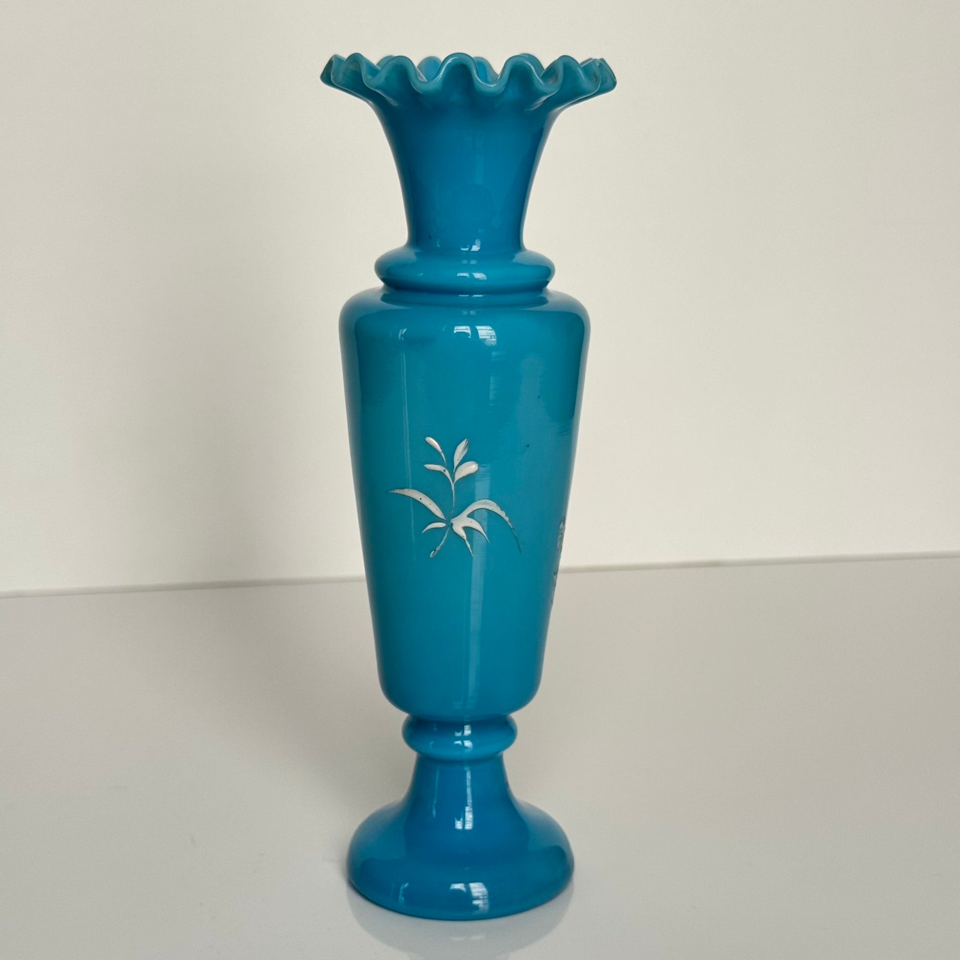 English: Blue opaline glass vase in Mary Gregory style, depicting a Victorian child blowing bubbles, hand-painted white enamel design; 日本語: メアリー・グレゴリー風の青いオパリンガラスの花瓶、シャボン玉を吹くヴィクトリア時代の子供を描いた手描き白エナメル装飾; Français: Vase en verre opalin bleu dans le style de Mary Gregory, décoré d’un enfant victorien soufflant des bulles, émaillé blanc peint à la main.