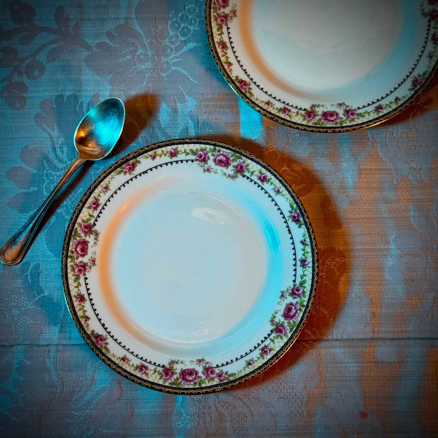 Pair of antique French Limoges porcelain dessert plates, 20th century. Delicate pink rose pattern on the rim, classic and elegant design.