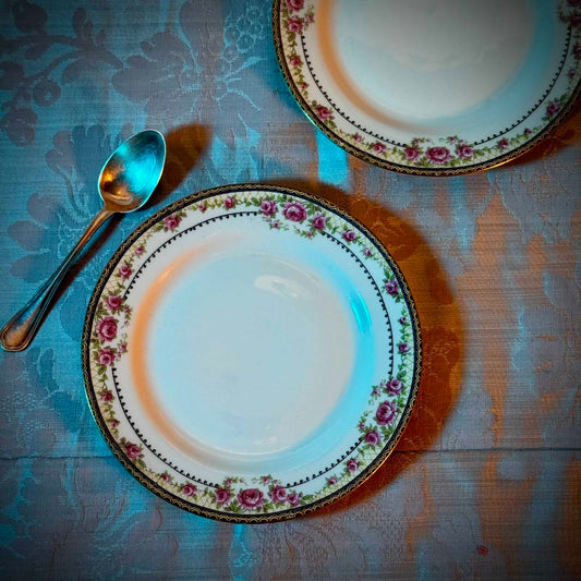 Pair of antique French Limoges porcelain dessert plates, 20th century. Delicate pink rose pattern on the rim, classic and elegant design.