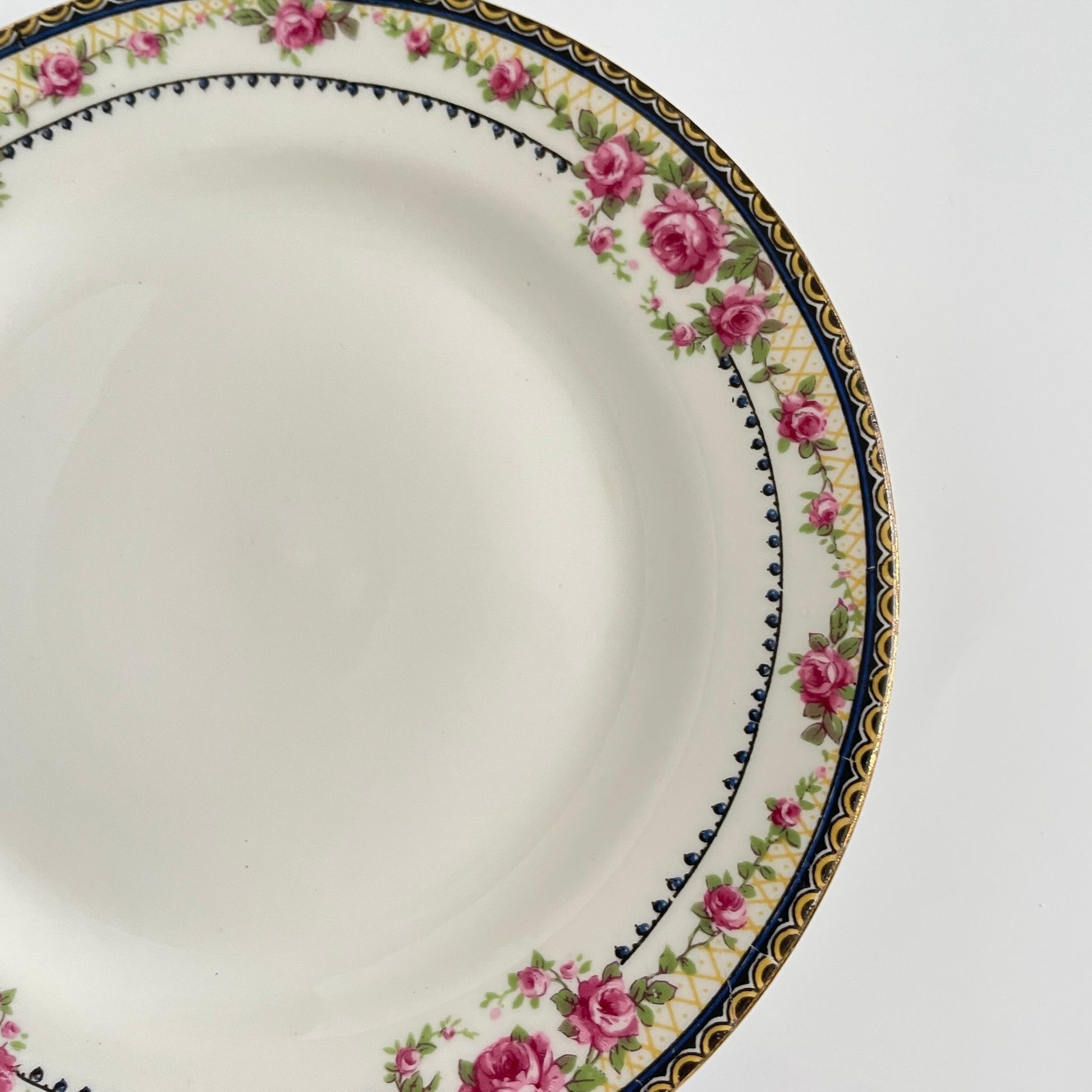 Pair of antique French Limoges porcelain dessert plates, 20th century. Delicate pink rose pattern on the rim, classic and elegant design.