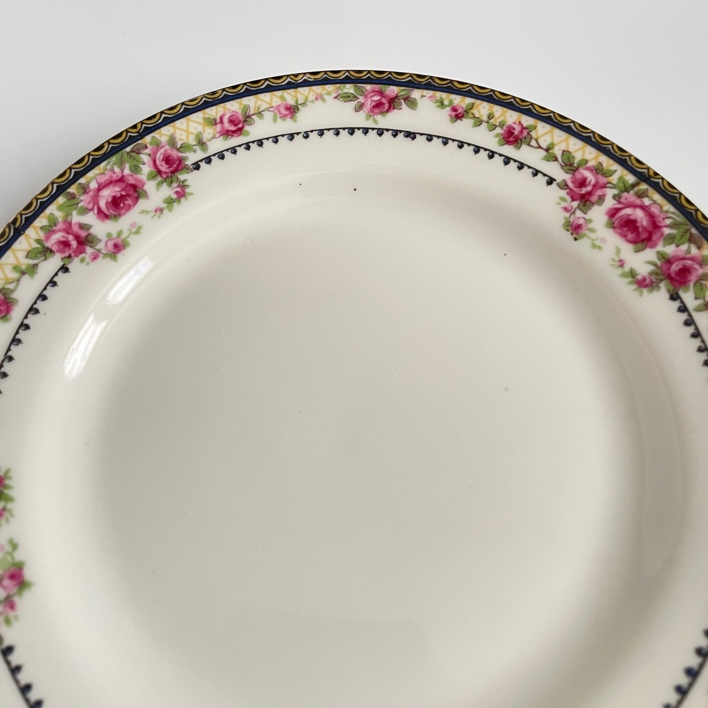 Pair of antique French Limoges porcelain dessert plates, 20th century. Delicate pink rose pattern on the rim, classic and elegant design.