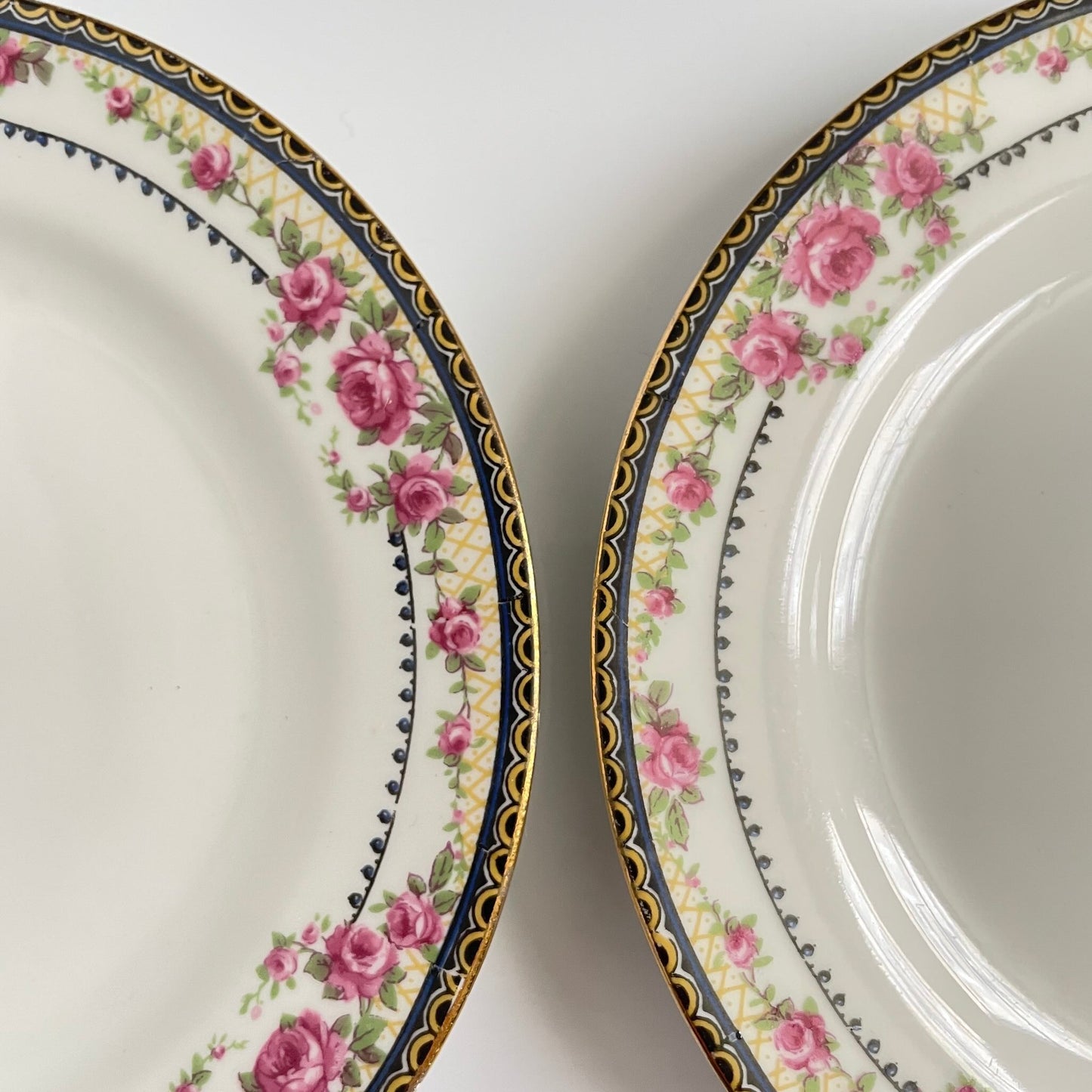 Pair of antique French Limoges porcelain dessert plates, 20th century. Delicate pink rose pattern on the rim, classic and elegant design.