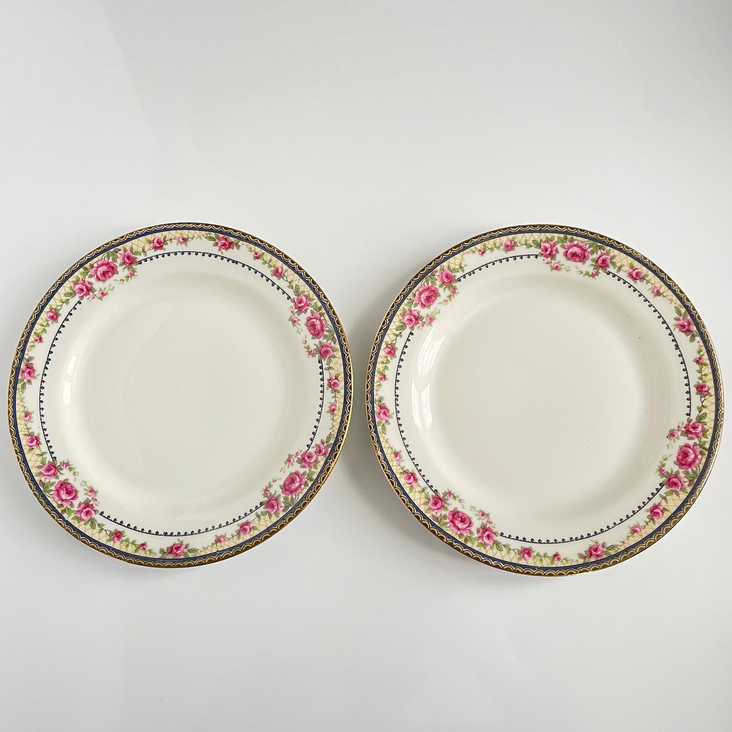 Pair of antique French Limoges porcelain dessert plates, 20th century. Delicate pink rose pattern on the rim, classic and elegant design.