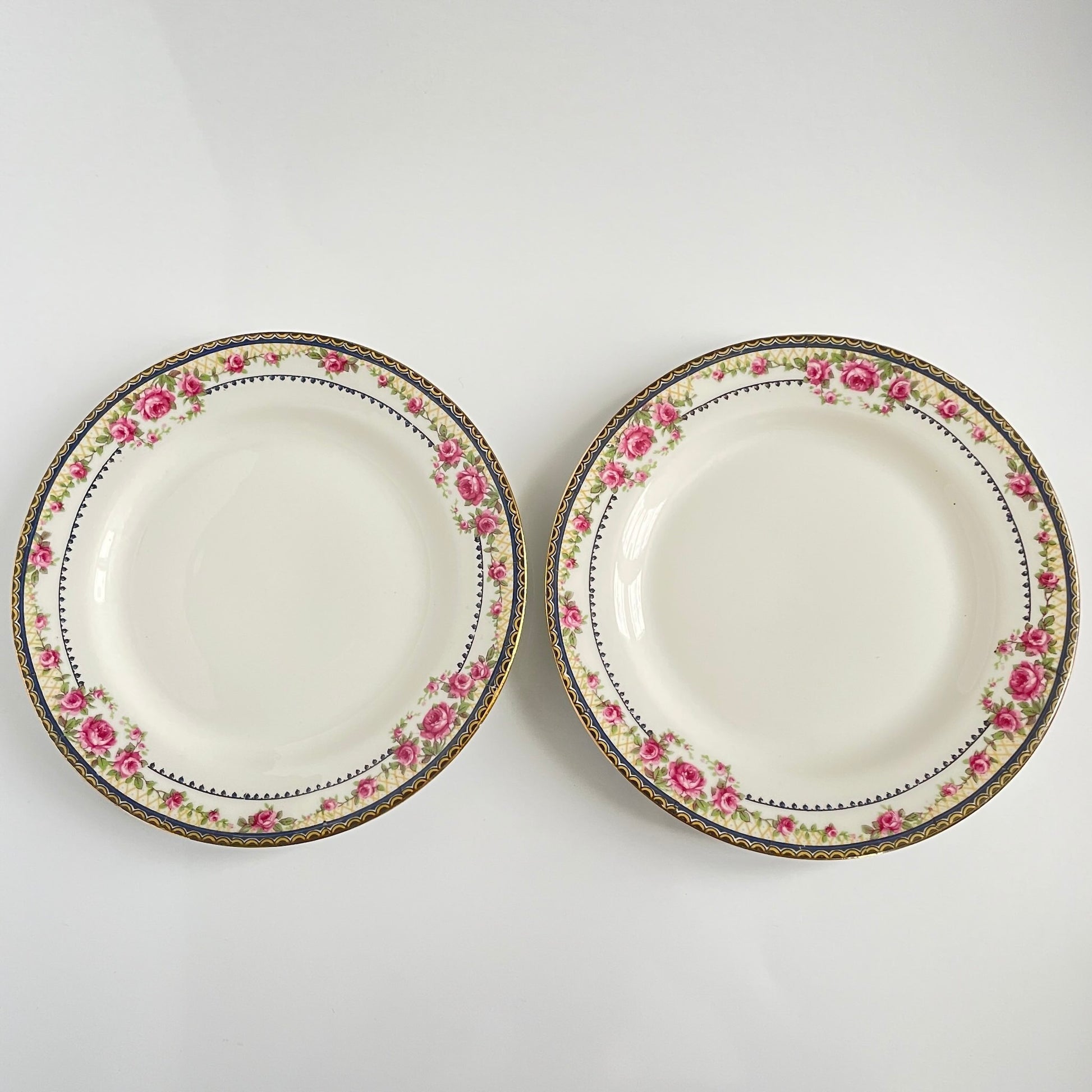 Pair of antique French Limoges porcelain dessert plates, 20th century. Delicate pink rose pattern on the rim, classic and elegant design.