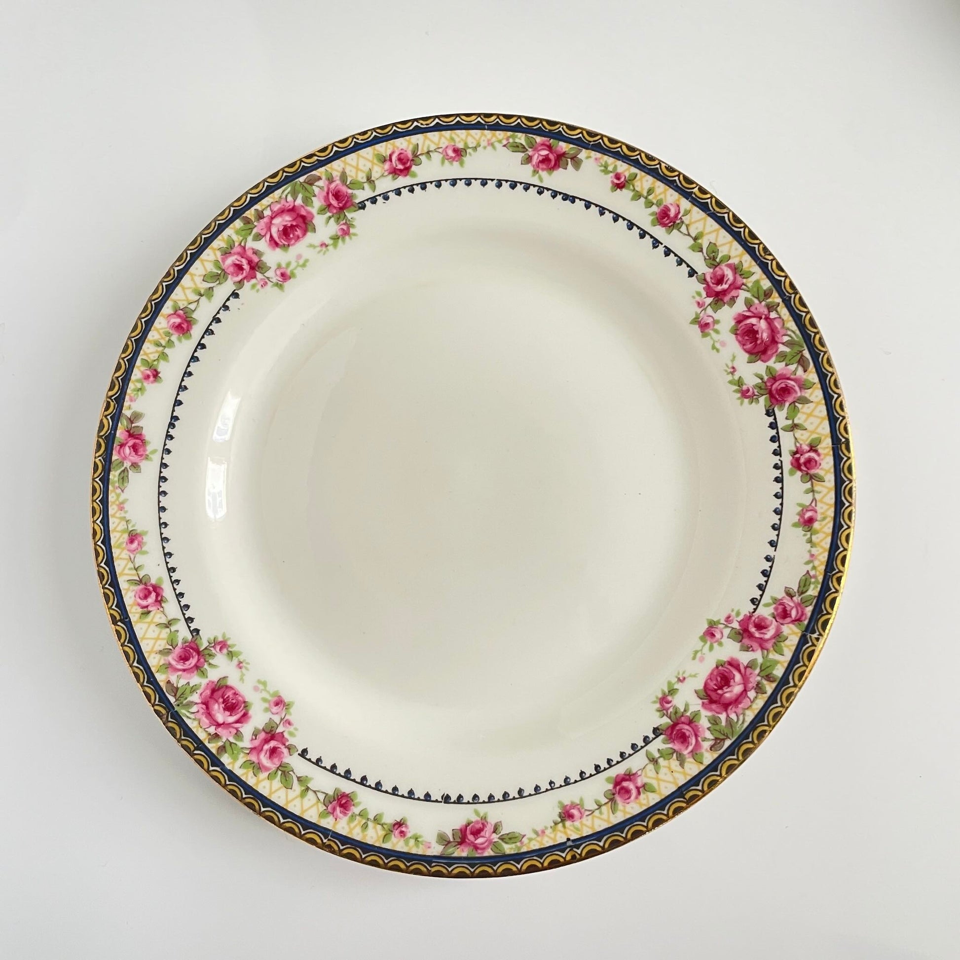 Pair of antique French Limoges porcelain dessert plates, 20th century. Delicate pink rose pattern on the rim, classic and elegant design.