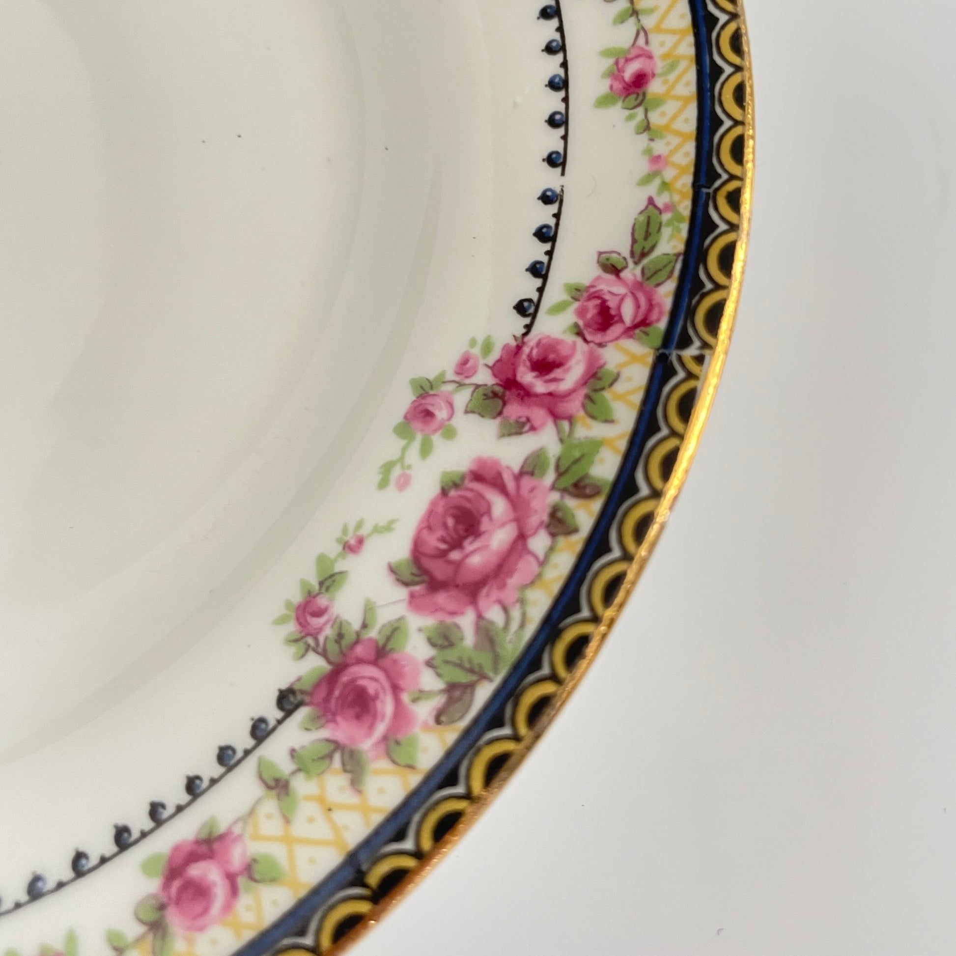 Pair of antique French Limoges porcelain dessert plates, 20th century. Delicate pink rose pattern on the rim, classic and elegant design.