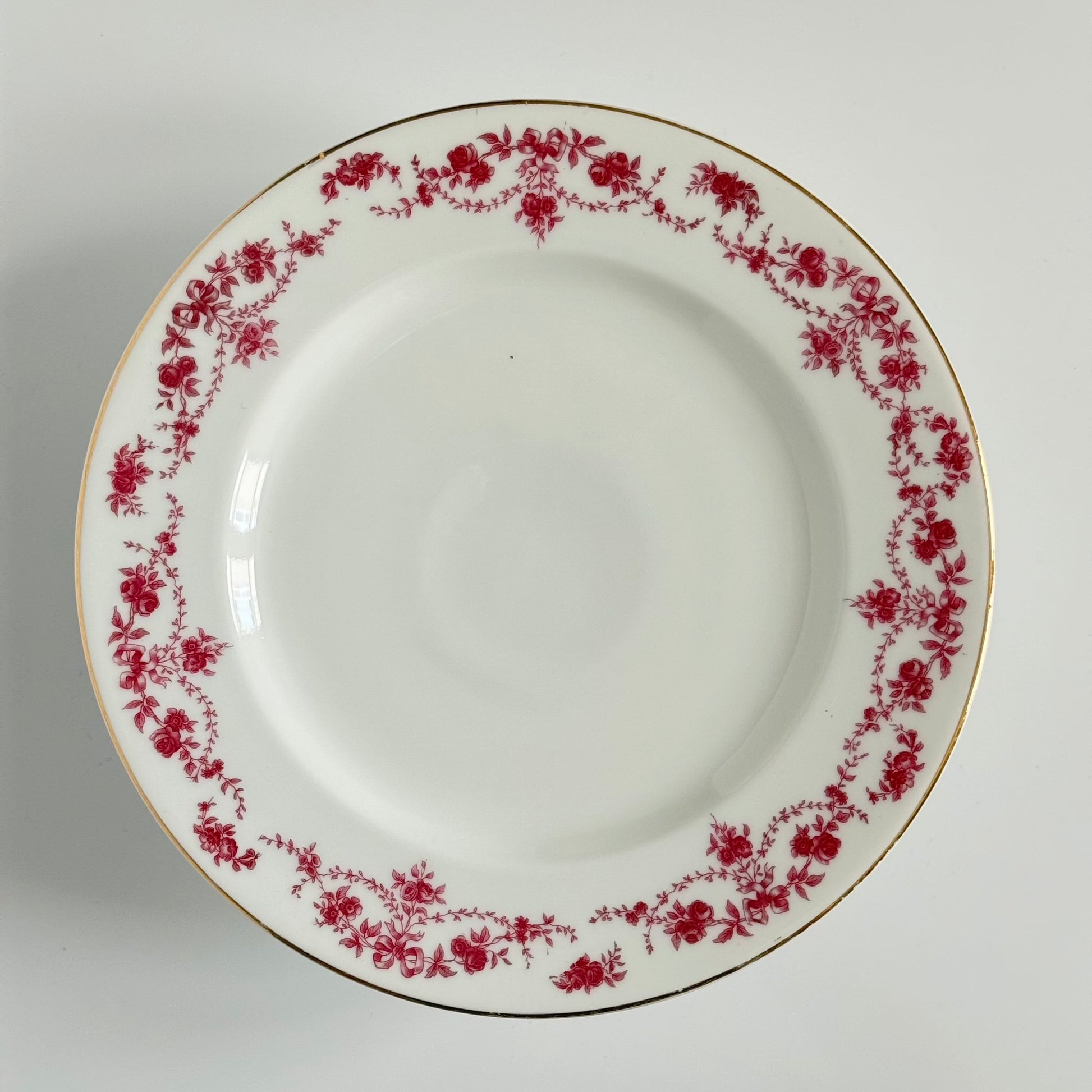 English: Antique Pirkenhammer porcelain cake stand decorated with ribbon and floral garland motif in pink and violet, early 20th century. ; Français : Présentoir à gâteau en porcelaine Pirkenhammer, décor de rubans et guirlandes florales rose/violet, début XXᵉ siècle. ; 日本語： ピルケンハンマー製アンティークケーキスタンド、ピンクパープルのリボンと花のガーランド装飾、20世紀初頭。