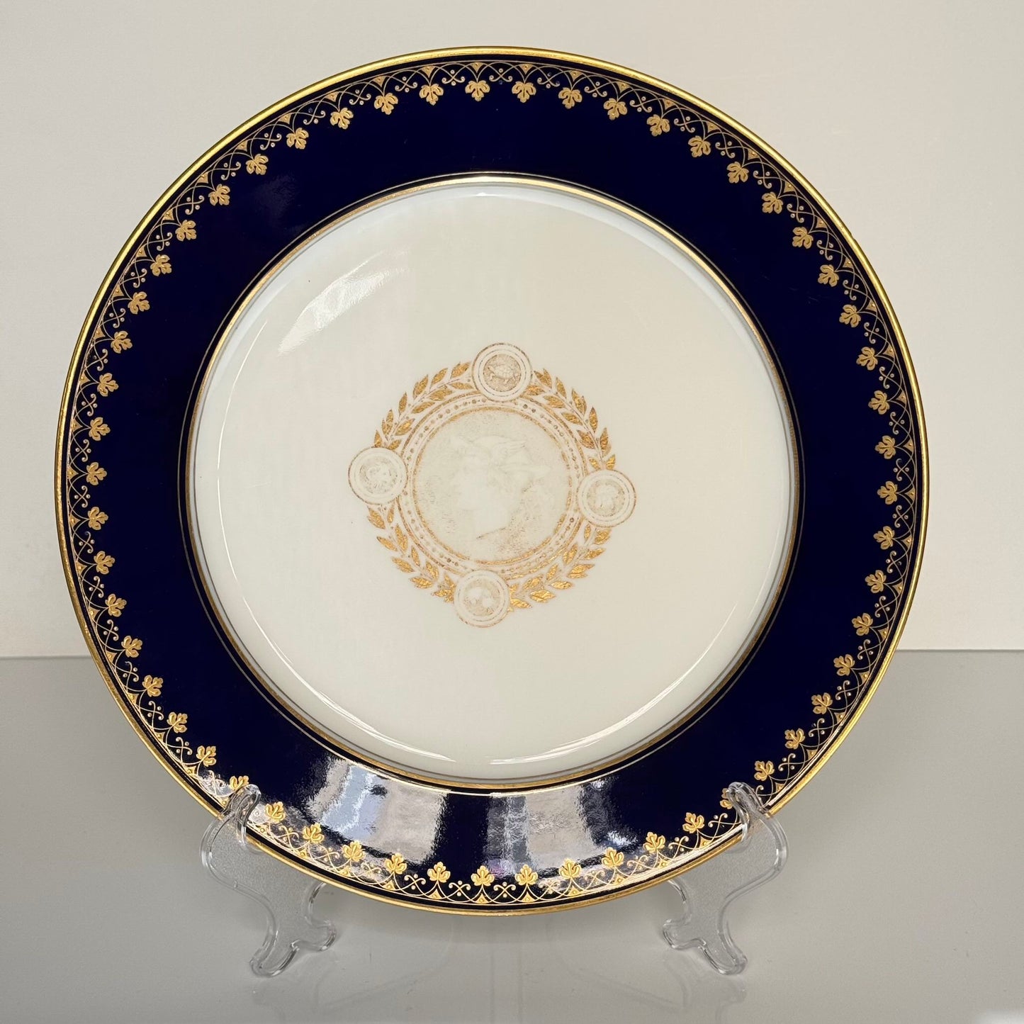 English: Sèvres porcelain plate, neoclassical style, with cobalt-blue border and gilded motifs of Mercury, laurel leaves, and symbolic animals, 1882–1883; 日本語: セーヴル製磁器プレート、新古典主義様式、コバルトブルーの縁に金彩装飾、メルクリウスと象徴的な動物、1882–1883年; Français: Assiette en porcelaine de Sèvres, style néoclassique, bordure bleu de Sèvres et motifs dorés de Mercure, laurier et animaux symboliques, 1882–1883.