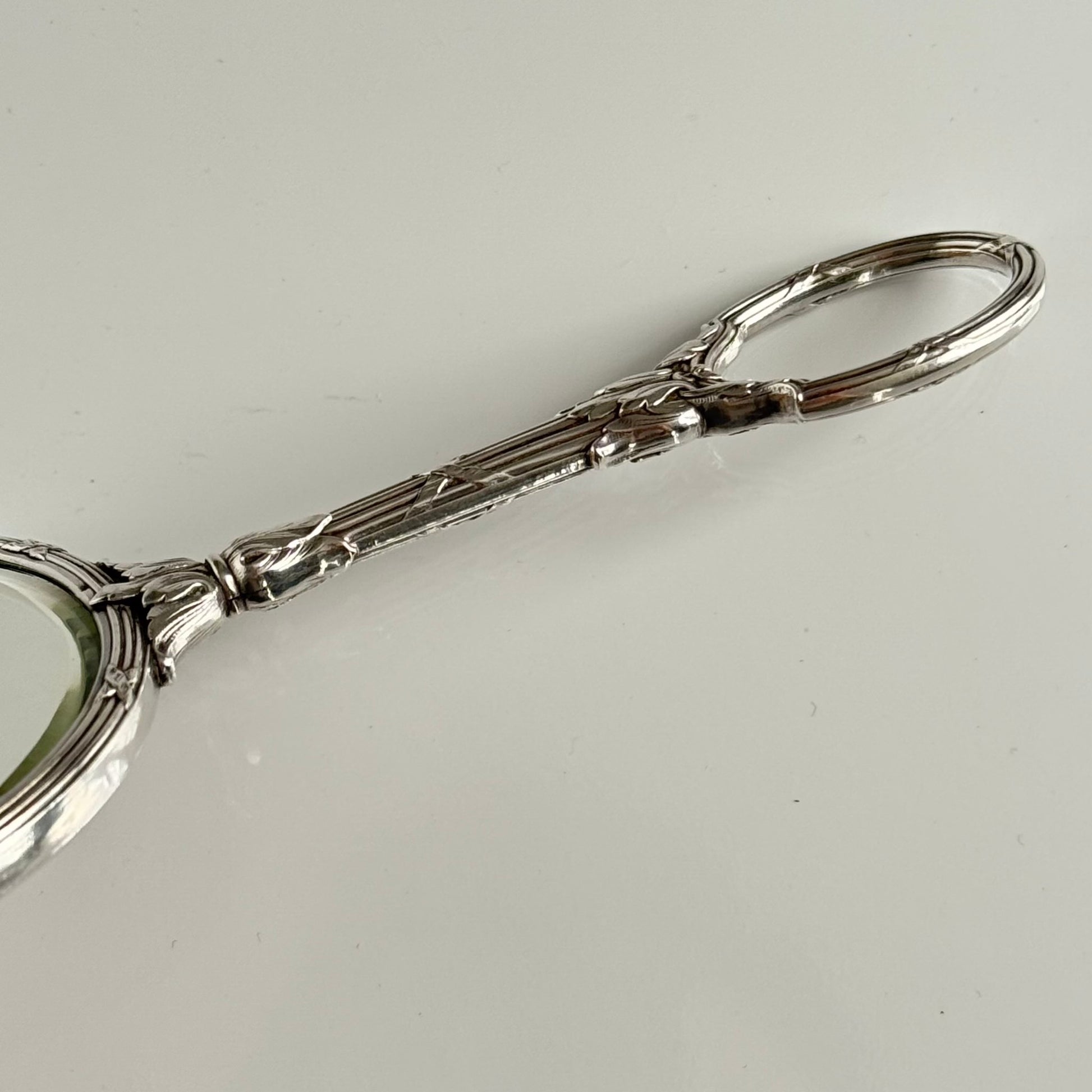 English: Silver plate hand mirror in Louis XVI style with crossed ribbons and decorative bow, late 19th to early 20th century, double-sided mirror ; 日本語: ルイ16世様式の銀メッキ手鏡、リボンと装飾的な結び目付き、19世紀末～20世紀初頭、両面鏡 ; Français: Miroir à main en métal argenté style Louis XVI avec rubans croisés et nœud, fin XIXe – début XXe siècle, miroir double face.