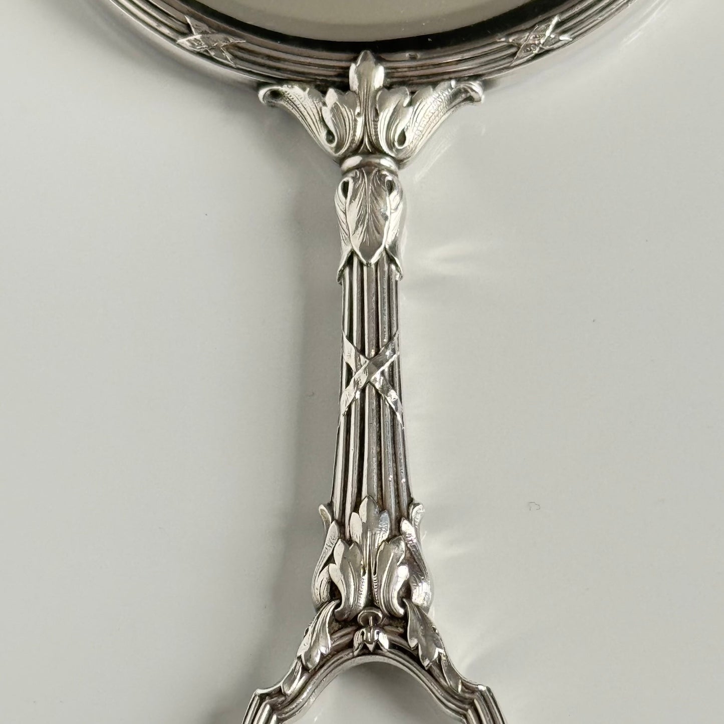 English: Silver plate hand mirror in Louis XVI style with crossed ribbons and decorative bow, late 19th to early 20th century, double-sided mirror ; 日本語: ルイ16世様式の銀メッキ手鏡、リボンと装飾的な結び目付き、19世紀末～20世紀初頭、両面鏡 ; Français: Miroir à main en métal argenté style Louis XVI avec rubans croisés et nœud, fin XIXe – début XXe siècle, miroir double face.
