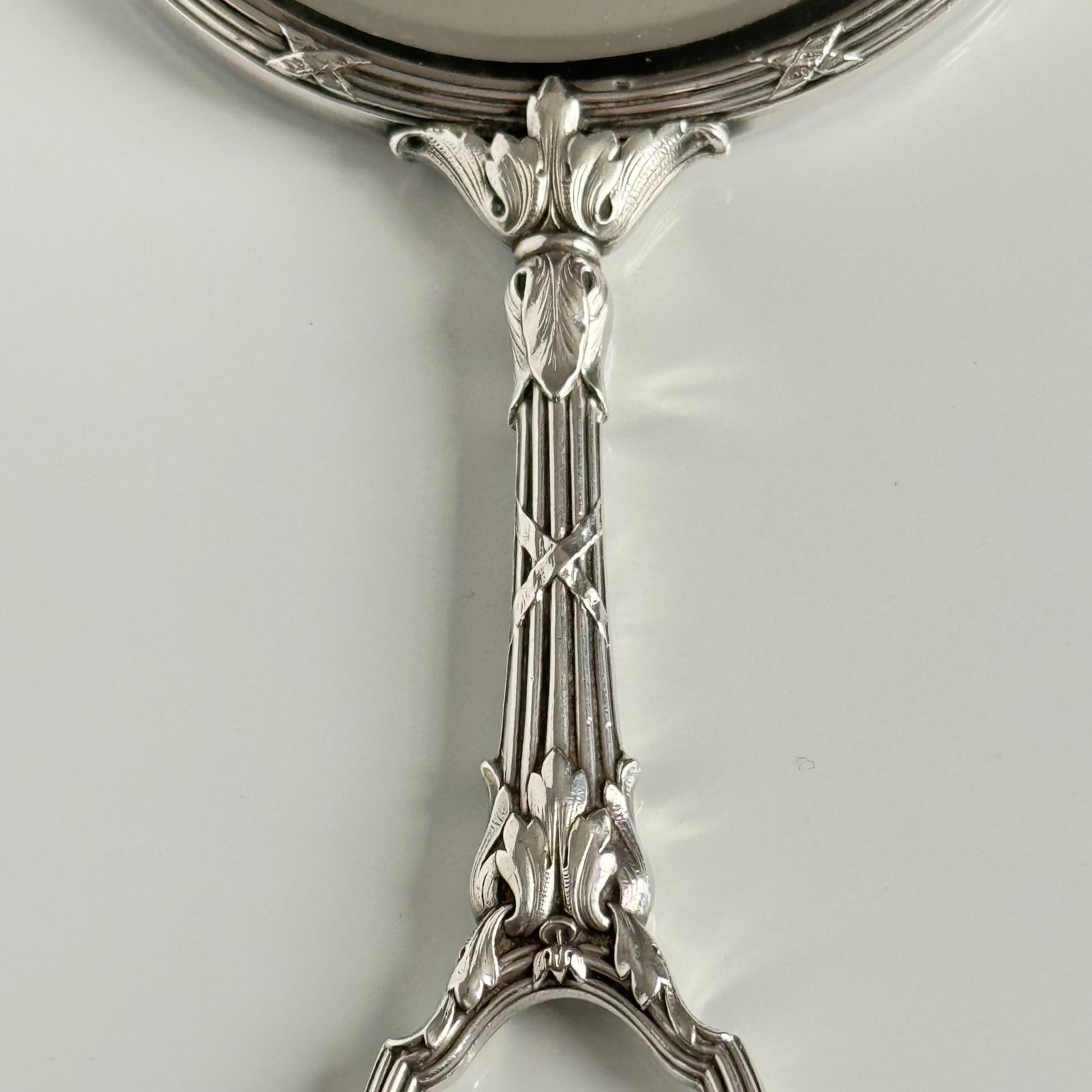 English: Silver plate hand mirror in Louis XVI style with crossed ribbons and decorative bow, late 19th to early 20th century, double-sided mirror ; 日本語: ルイ16世様式の銀メッキ手鏡、リボンと装飾的な結び目付き、19世紀末～20世紀初頭、両面鏡 ; Français: Miroir à main en métal argenté style Louis XVI avec rubans croisés et nœud, fin XIXe – début XXe siècle, miroir double face.