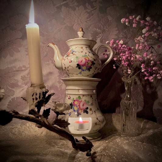 This is a Paris porcelain tisanière (herbal teapot with warmer) from the early 20th century. It features a hand-painted polychrome floral design with gilded accents.