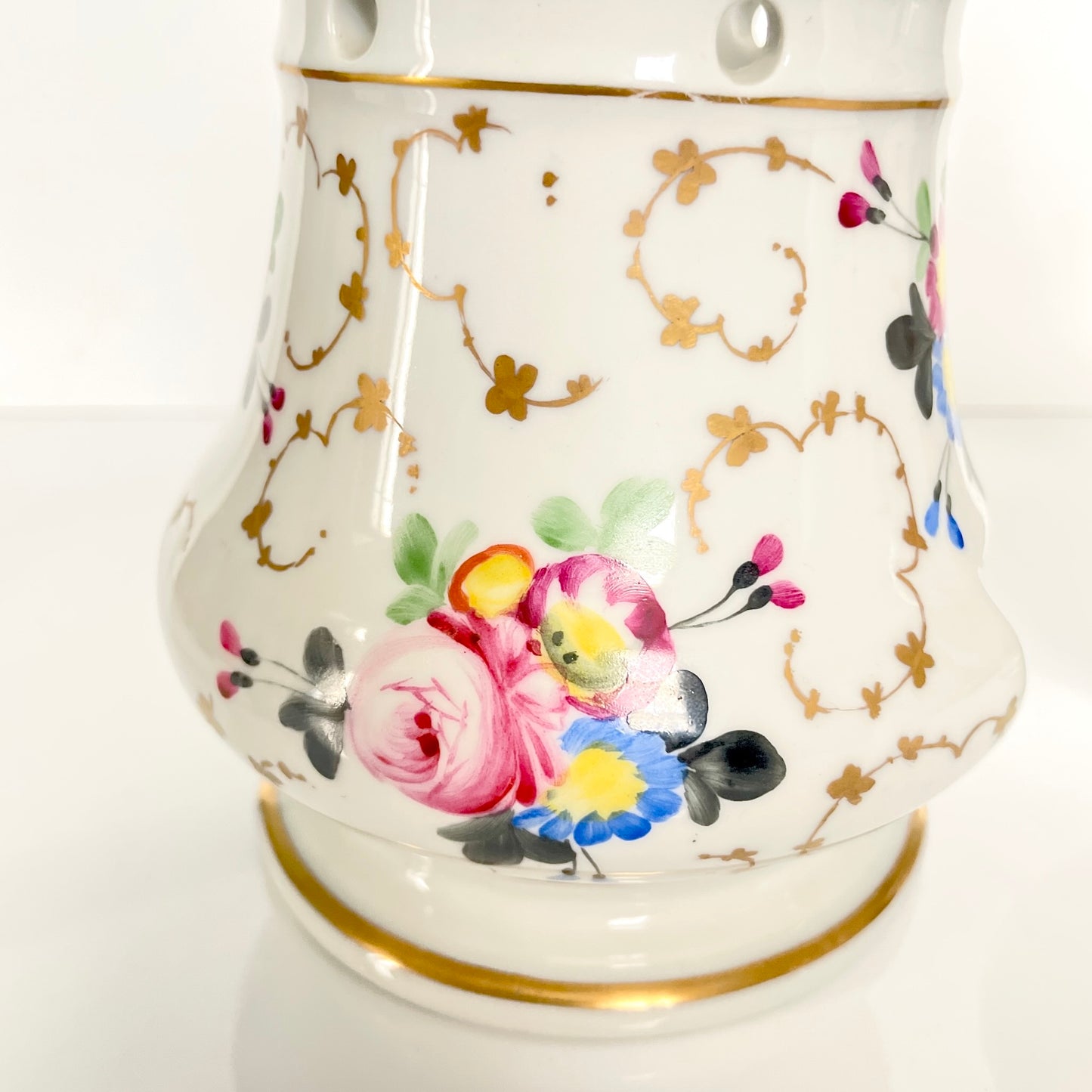 This is a Paris porcelain tisanière (herbal teapot with warmer) from the early 20th century. It features a hand-painted polychrome floral design with gilded accents.