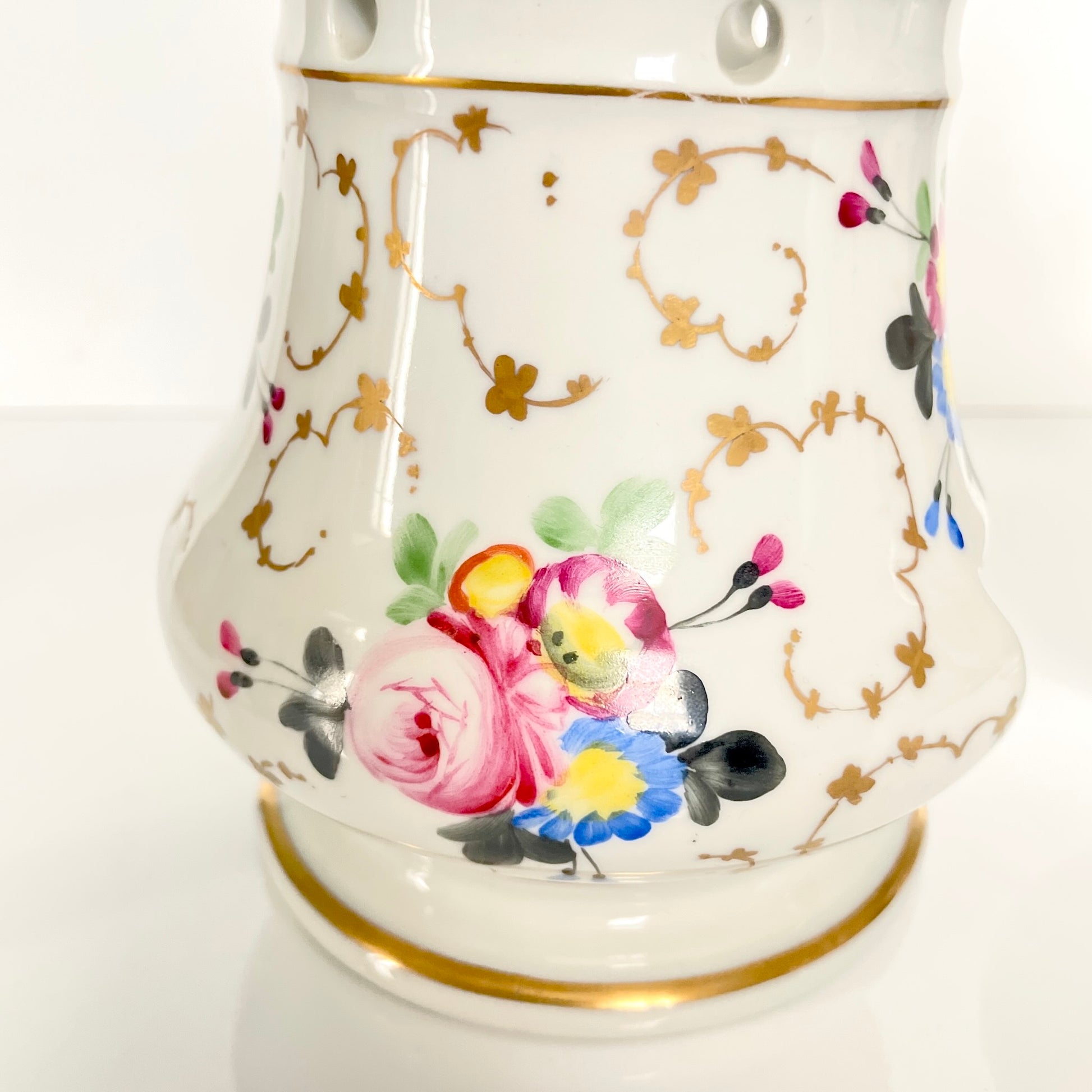 This is a Paris porcelain tisanière (herbal teapot with warmer) from the early 20th century. It features a hand-painted polychrome floral design with gilded accents.