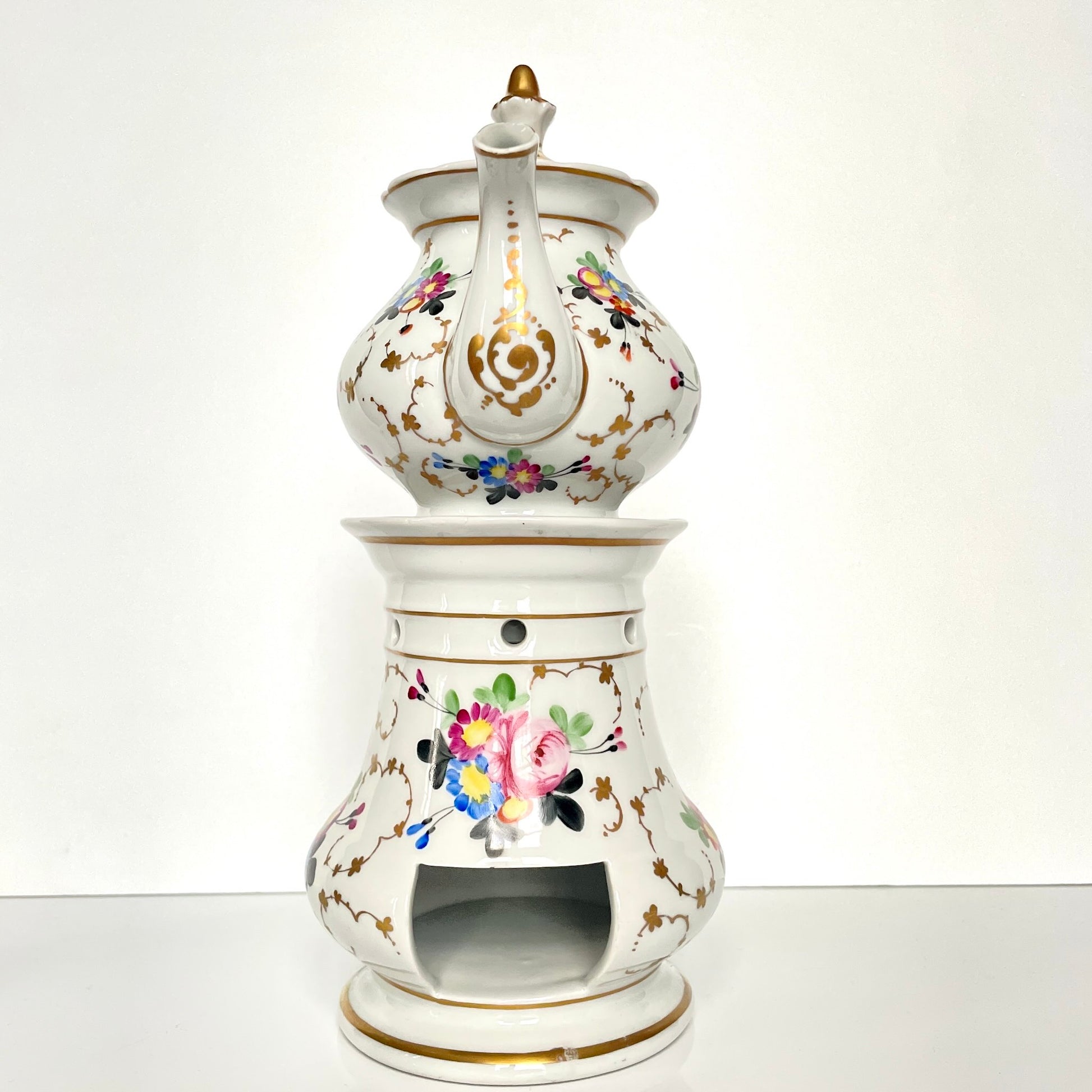 This is a Paris porcelain tisanière (herbal teapot with warmer) from the early 20th century. It features a hand-painted polychrome floral design with gilded accents.